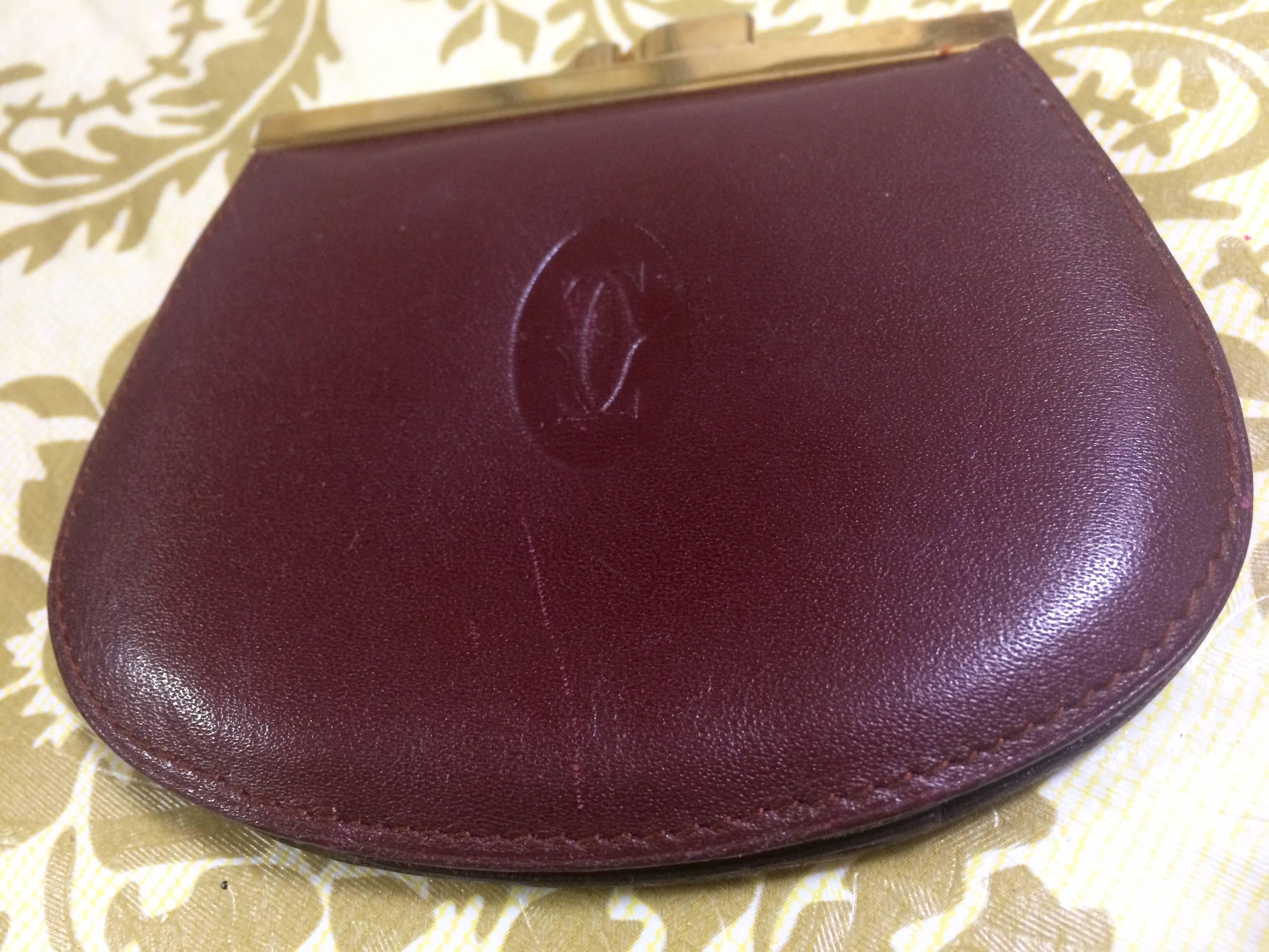 1990s.  Vintage Cartier genuine wine leather coin case wallet with gold tone kiss lock closure. must de Cartier. Unisex use.

This is a Cartier vintage coin case purse from the early 90's, must de Cartier collection. 
Classic leather coin wallet