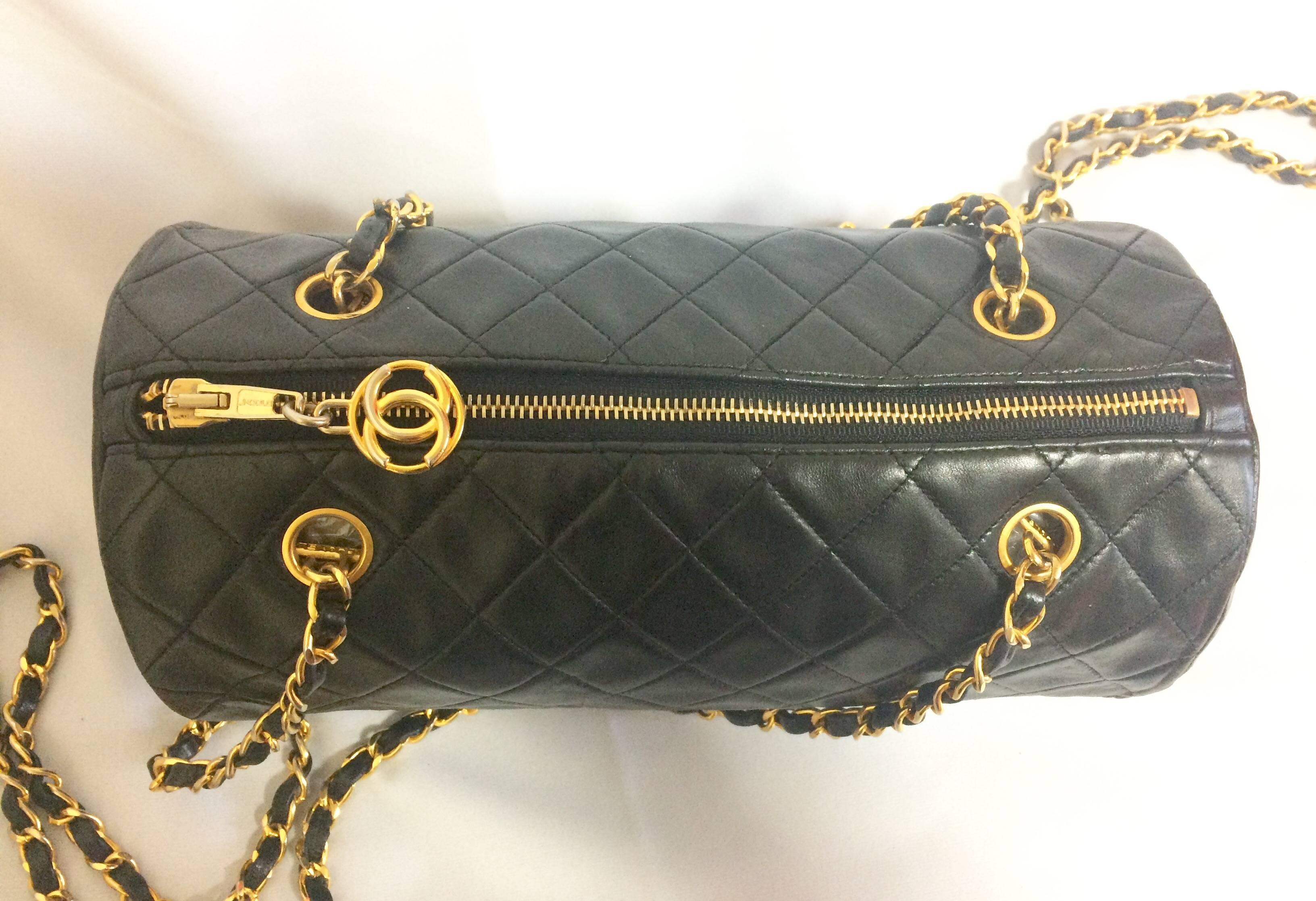 Women's Vintage CHANEL black lamb leather golden chain shoulder bag in round drum shape.