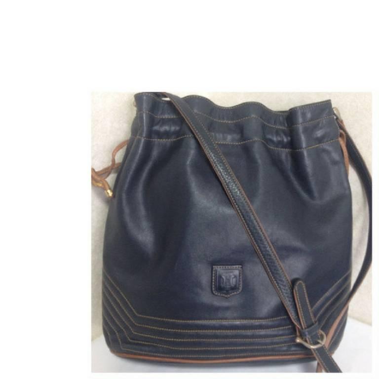 1990s. Vintage Celine navy leather hobo bucket shoulder bag with drawstrings and brown pipings. Unisex daily use purse.

Introducing another vintage masterpiece from CELINE back in the early 90's.

Classic bucket hop shoulder bag in navy genuine