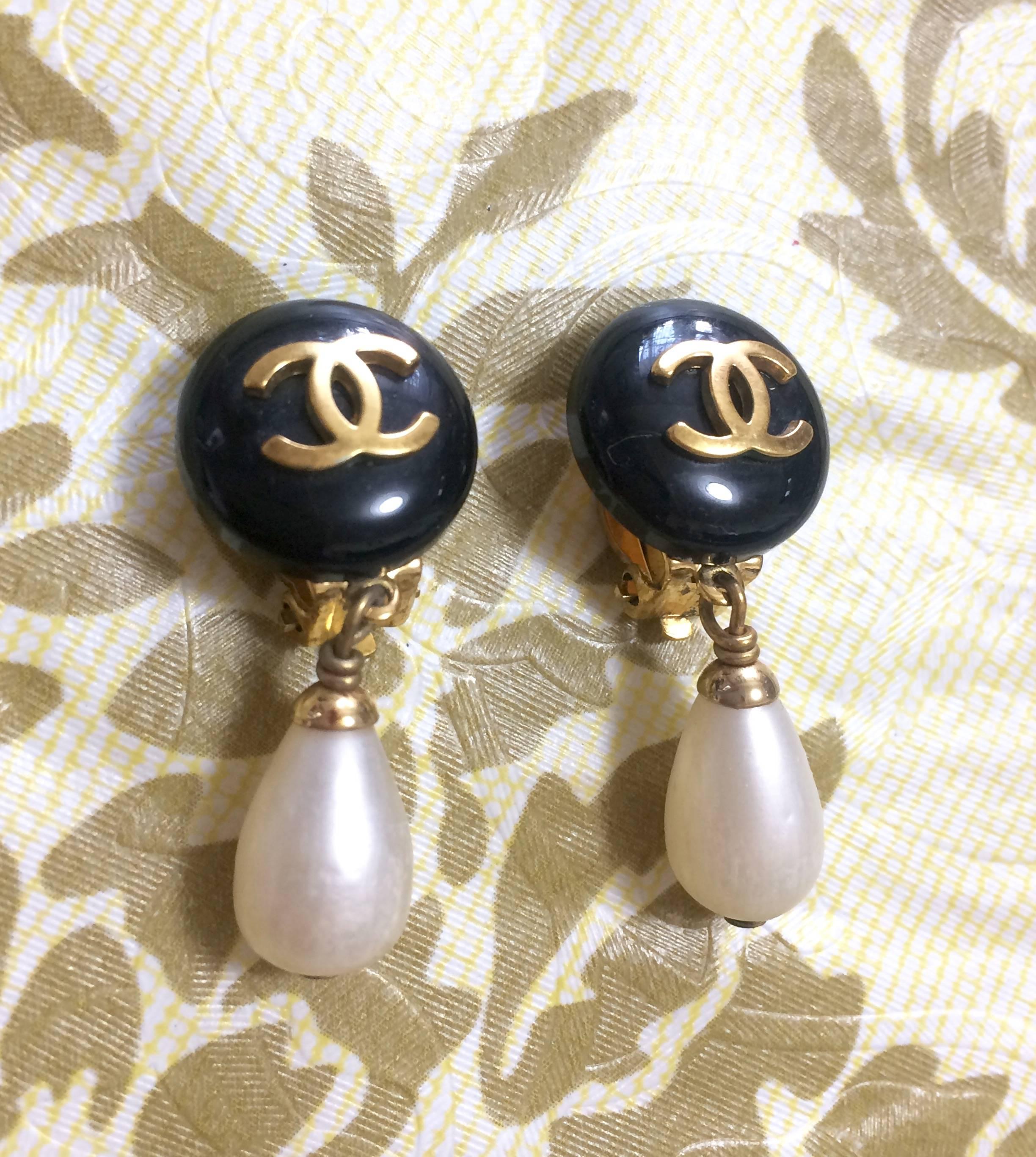 1990s. Vintage CHANEL teardrop white faux pearl earrings with black and golden CC mark on top. Chanel dangling earrings.

Introducing a vintage CHANEL faux teardrop pearl earrings with black round and golden CC marks on top. 
 
Wearing these