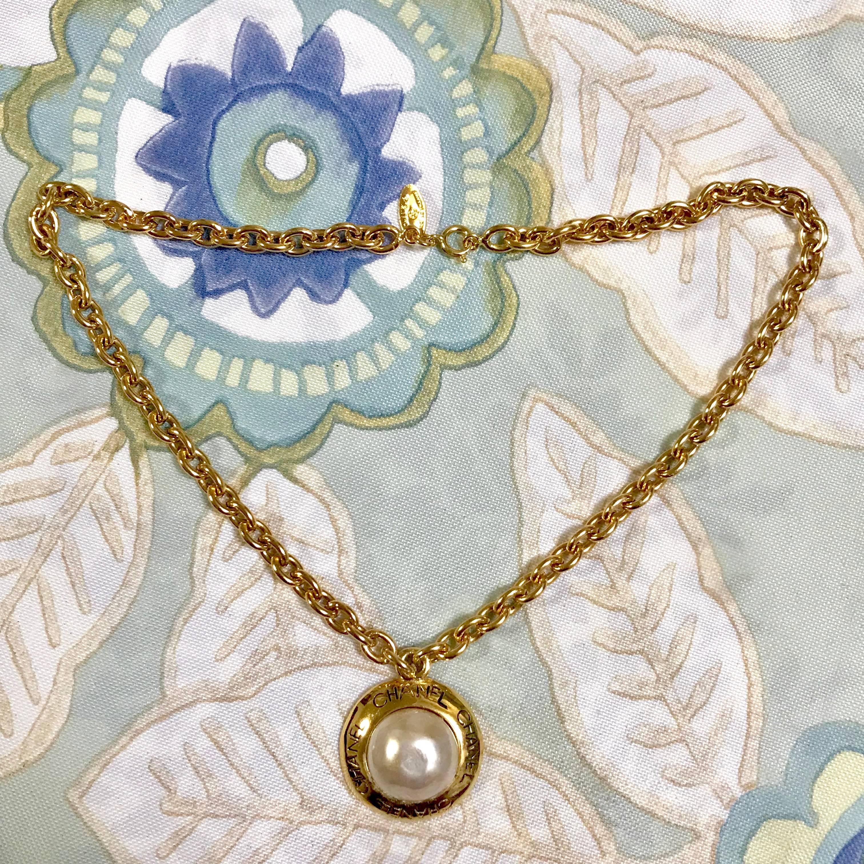 1980s. Vintage CHANEL golden chain necklace with round faux pearl and logo embossed charm pendant top. Classic Chanel jewelry from 80's. Beautiful piece.

Fun, chic and Gorgeous!  
Great gift idea. Free gift wrapping. 
Here is another classic
