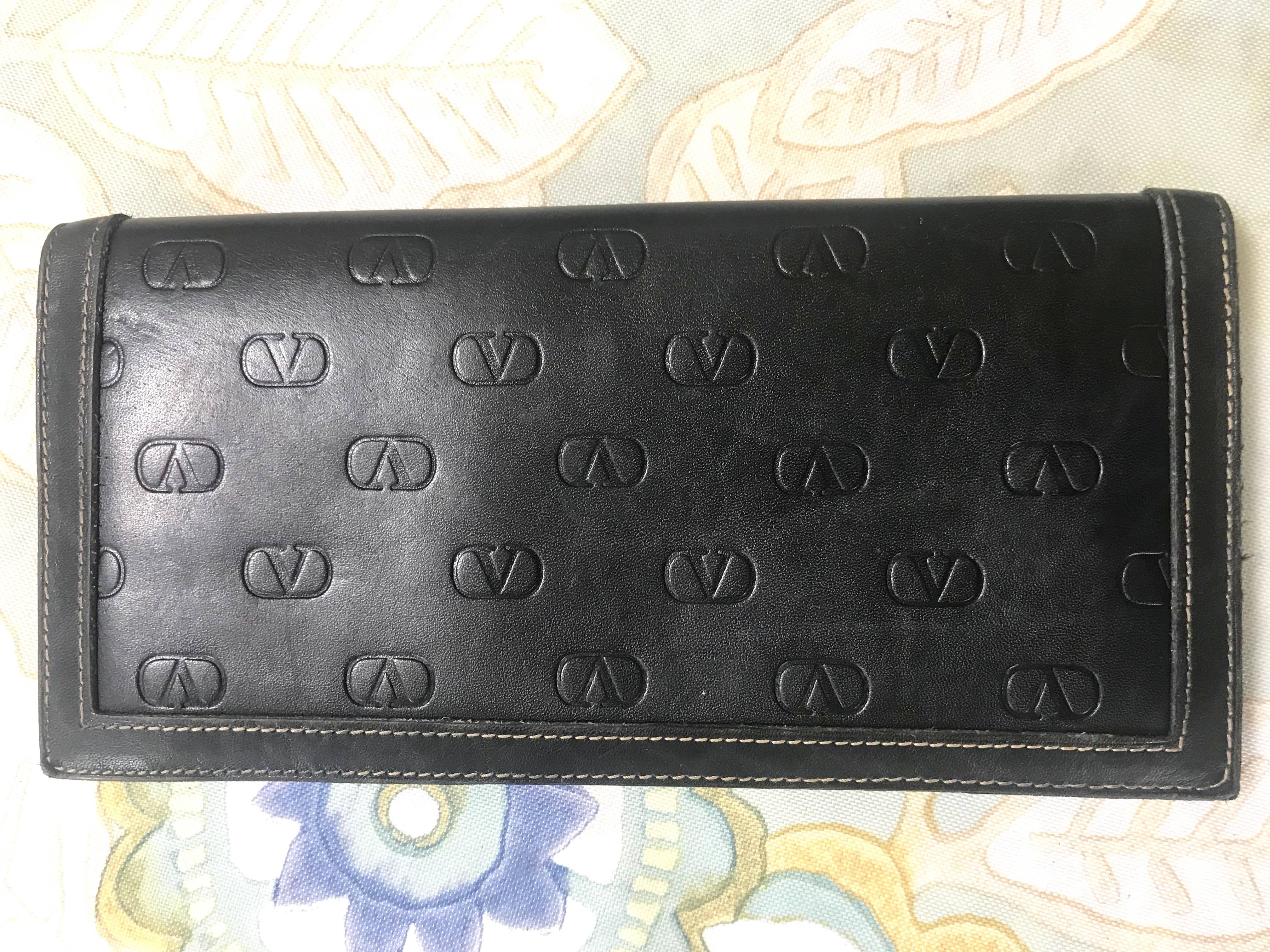 1980s. Vintage Valentino black leather long wallet with beige stitches and all over embossed logo. Unisex use. Classic purse.
Introducing a vintage Valentino's classic black leather long wallet featuring its iconic V logo embossed all over pn both