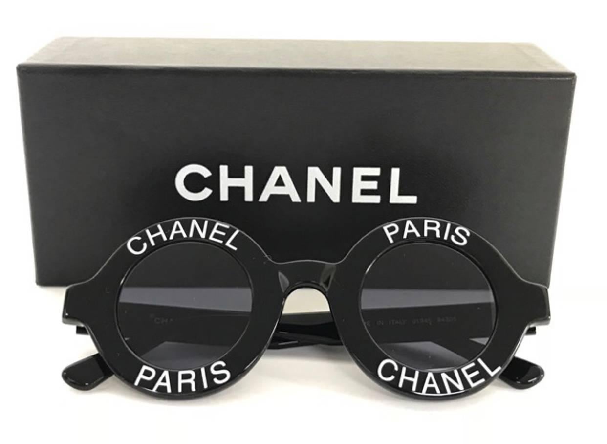 1990s. Vintage Chanel black round frame sunglasses with white CHANEL PARIS print on it. Must-have and very collective eyewear piece.

One-of-a-kind sunglasses back in the old era, back in 1993. 
These are vintage CHANEL black round frame sunglasses