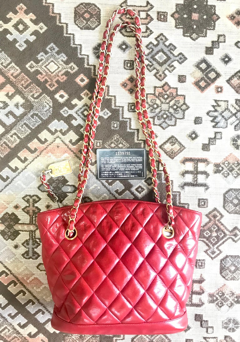 1980s. Vintage CHANEL lipstick red quilted lamb leather trapezoid shape tote bag with a gold CC plate and chains.

Introducing another vintage lambskin CHANEL in hot red color with gold-tone logo plate pull to the zipper from the 80's. 
The zipper