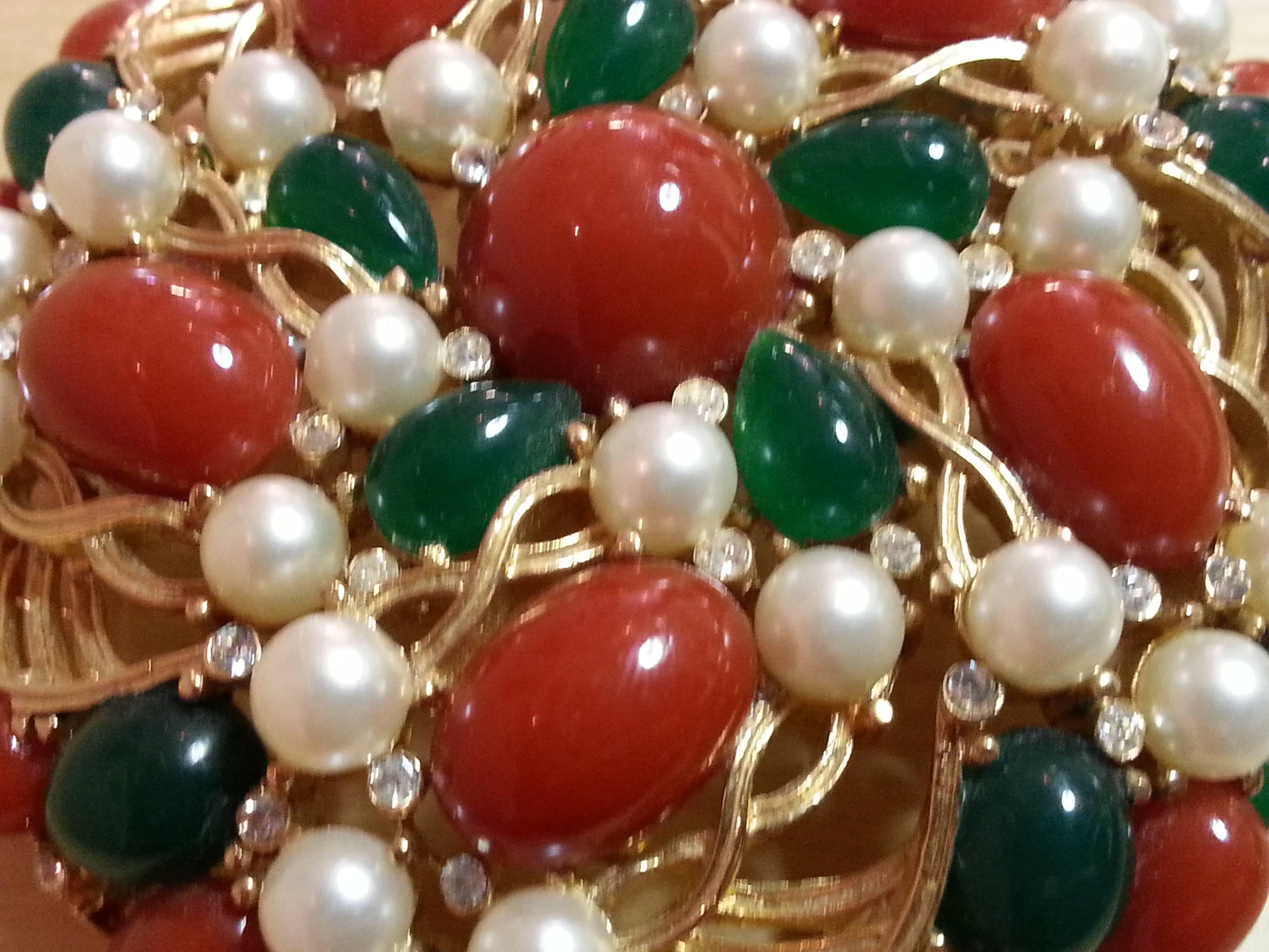 This large brushed goldtone TRIFARI pin dates from the 1960's and incorporates classic aspects of Mogul designed jewelry design in its period format. Flat backed faux emerald and coral cabochons provide rich color and texture in contrast to the