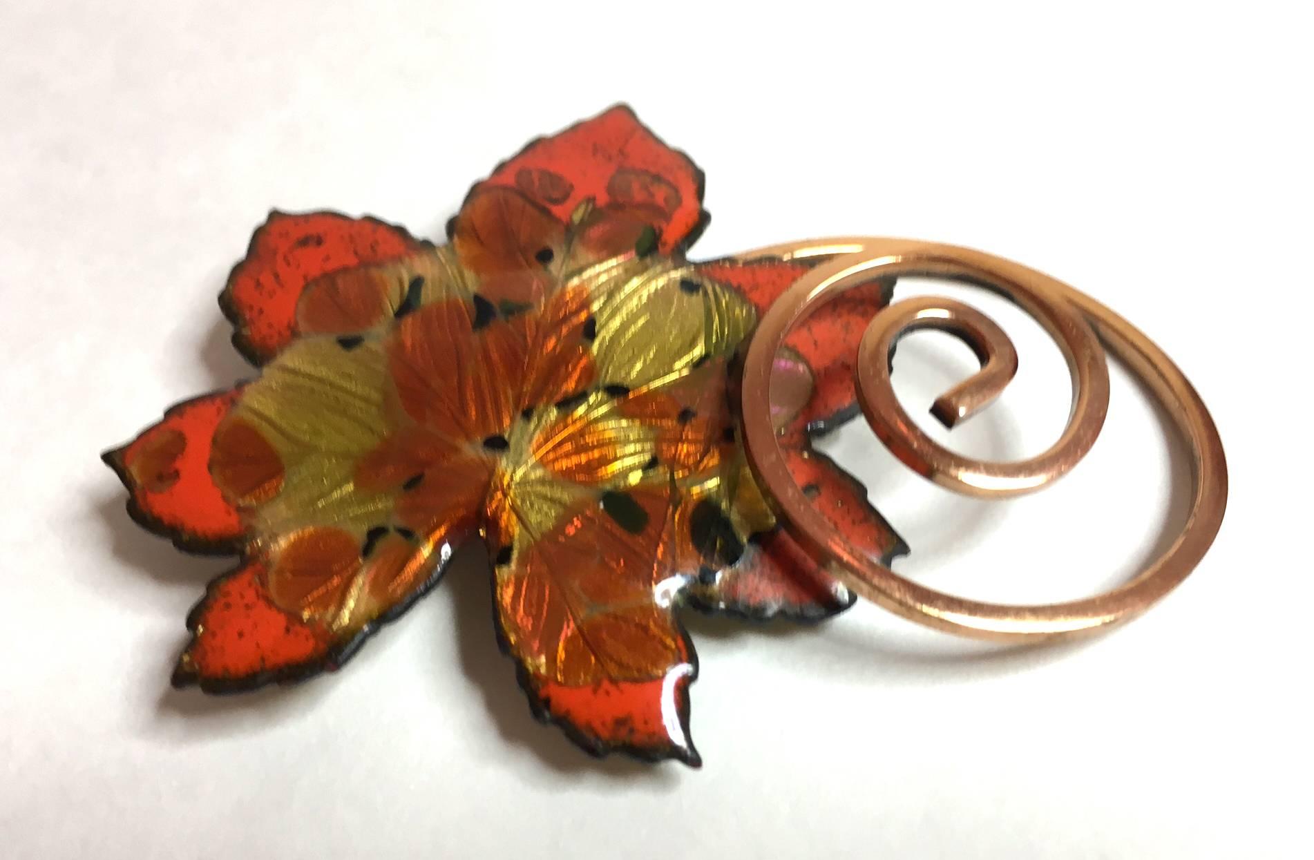 This copper and enamelled maple leaf brooch by Matisse ,a division of Renoir of California that specialized in enamelwork,  is executed in an elaborate multi-fired brilliant orange and multi colored enamel. Designed by Jerry Fels, who would later go