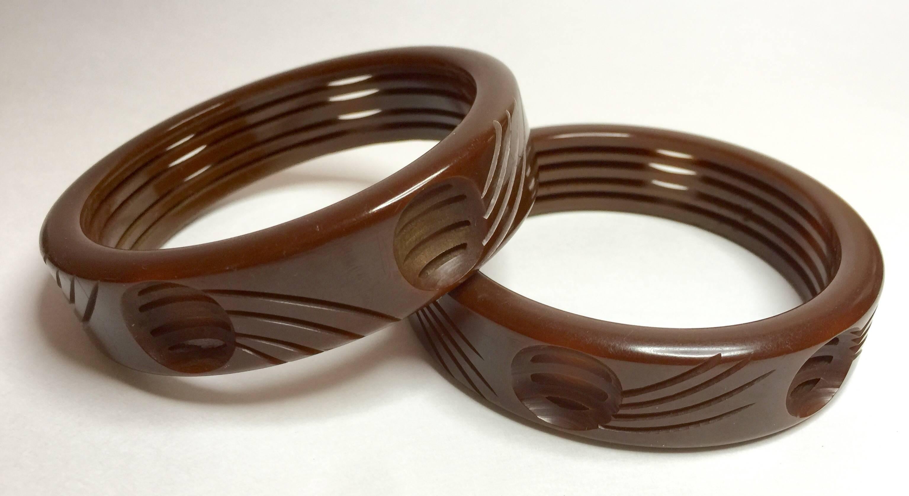 Sold as an identical twosome, these two (2) unusual brown bakelite bangles are stylish and wholly contemporary in tone. Their dimpled carved detail in combination with the unusual concentric cut-out carving on the interior of the bangles makes for