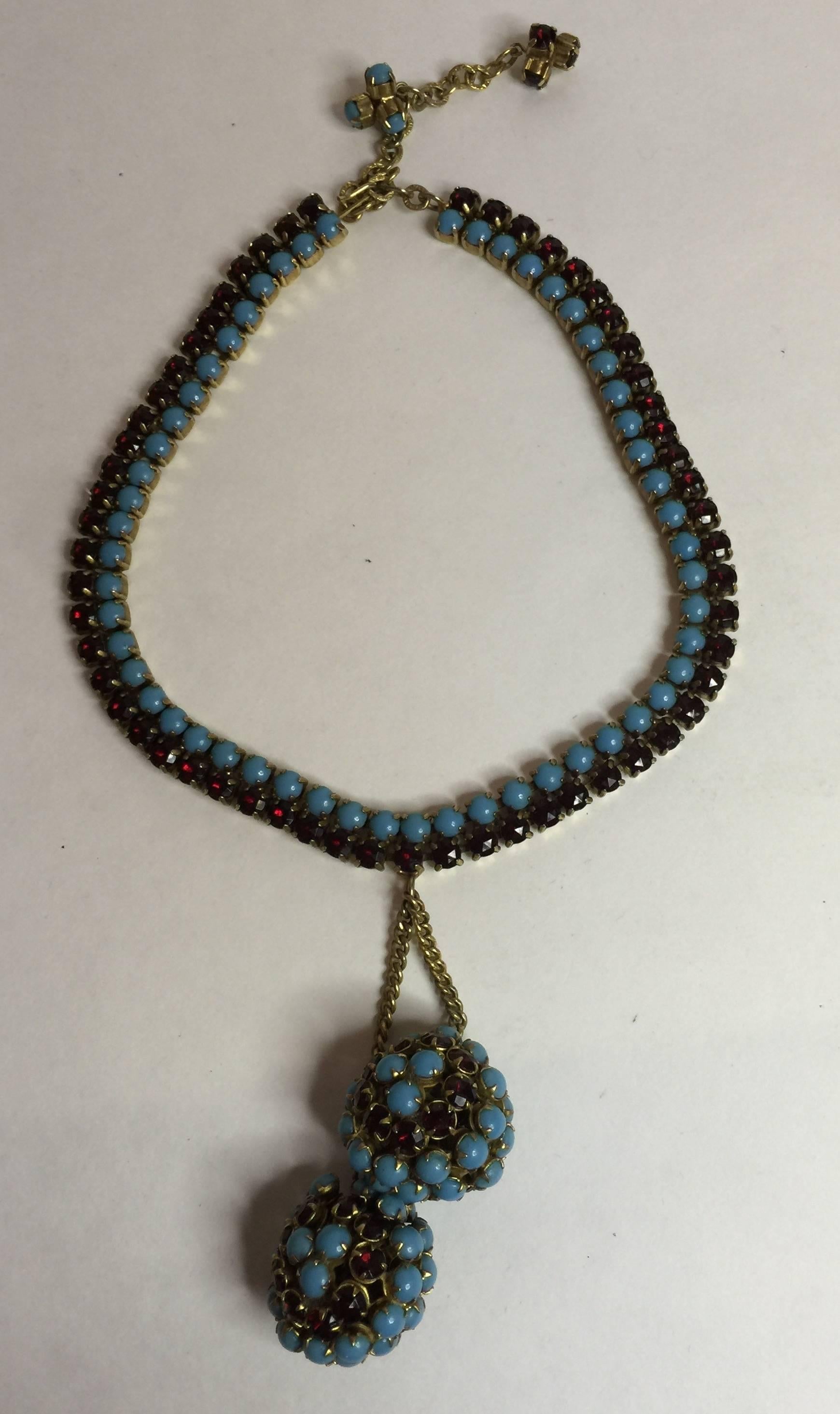 This 1950s HATTIE CARNEGIE Faux Turquoise and Ruby Retro Style Double Ball Drop Necklace is a highly elegant and unusually designed necklace with a classic stone color combination and asymmentrical design which is always alluring and appealing. The