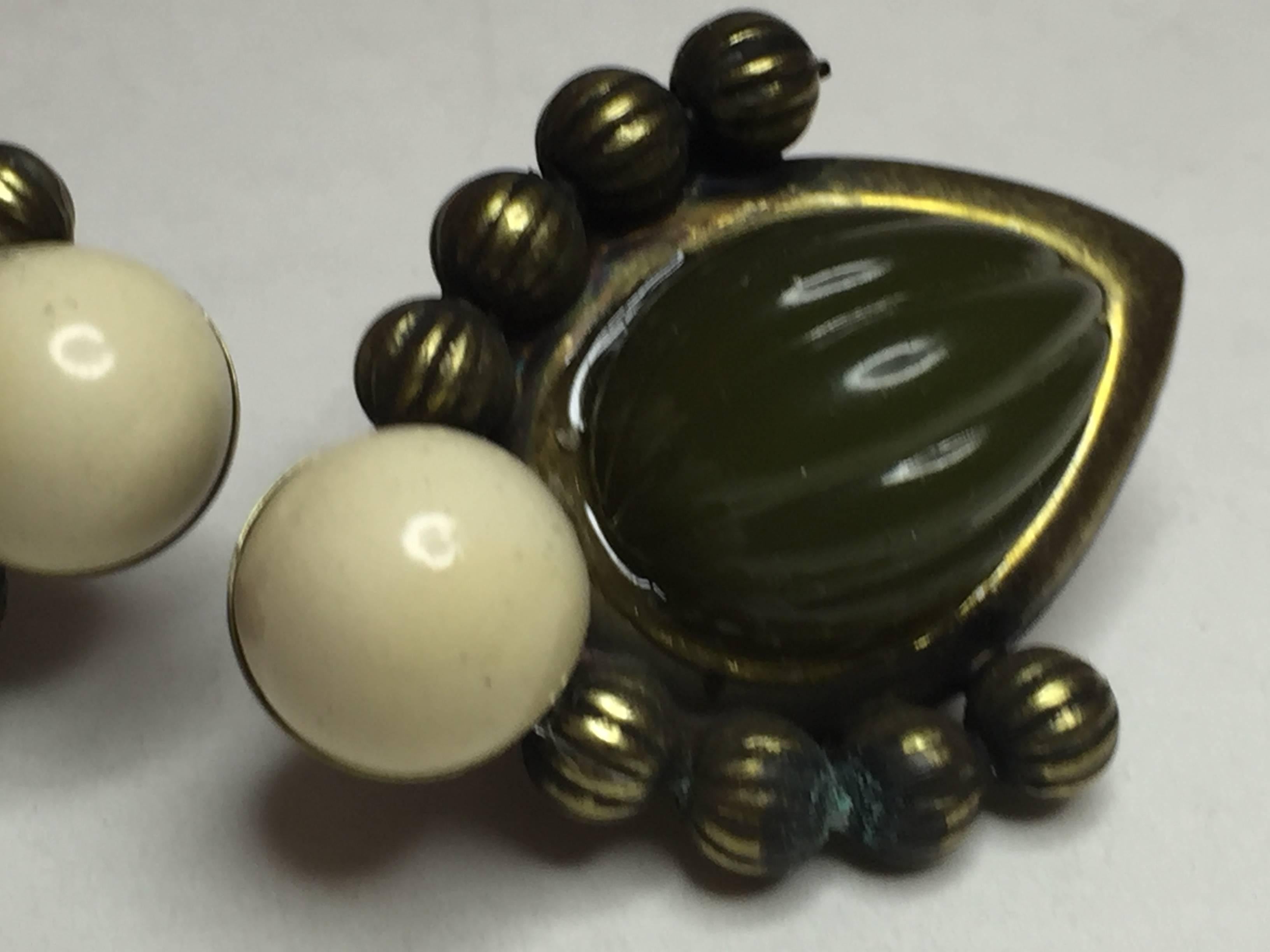 This classic resin and bead VRBA earring of manufacture and design in the past 10 years, is ressemblant of a green faux jade carved bakelite earring set in an antiqued gold  ball detailed setting. A cream celluloid like resin bead forms the terminus