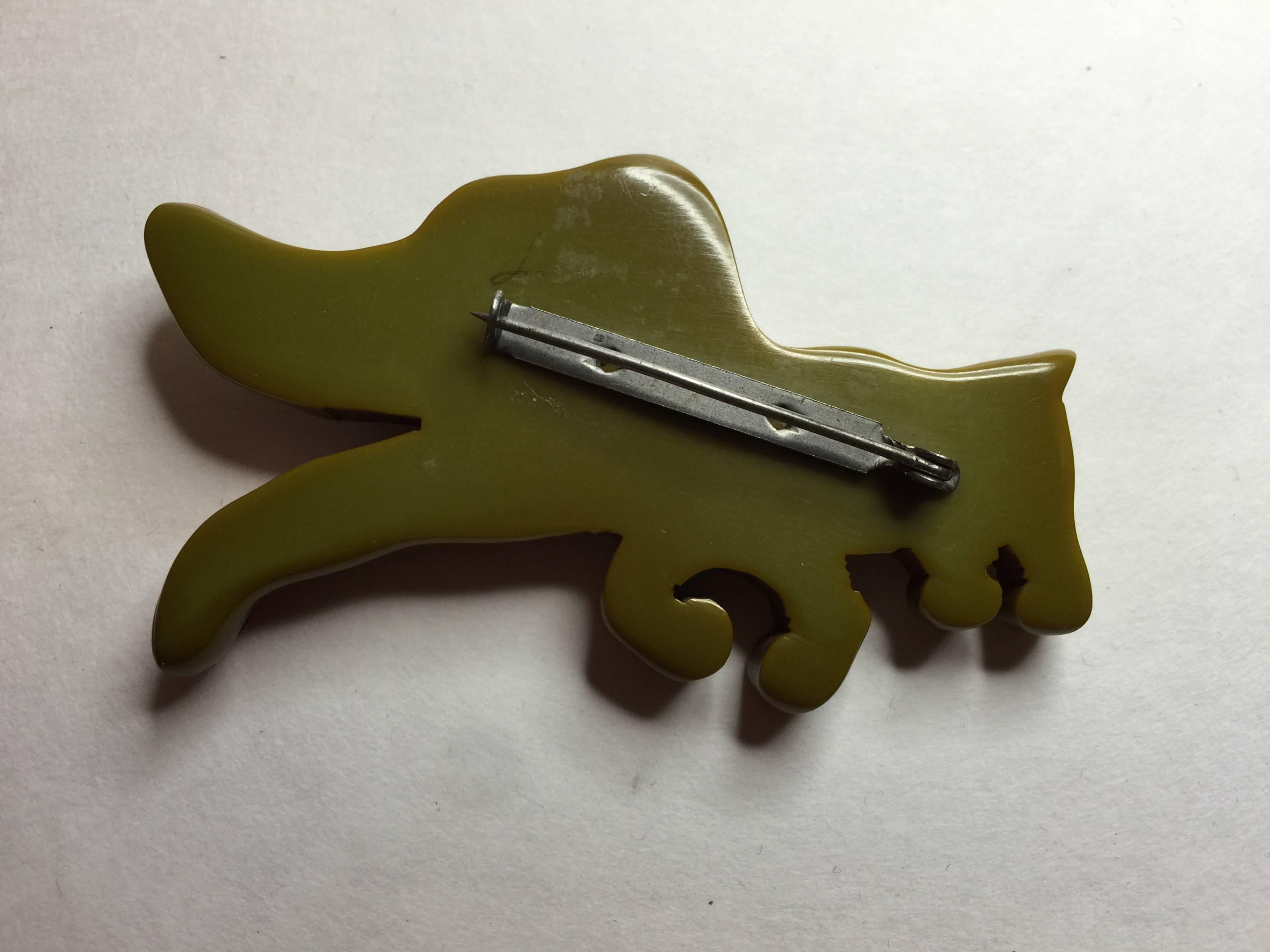This sweet figural bakelite dog pin is of the 1930s era, and is an olive green color bakelite with bright original folk art style painted detail.  Approximately 2