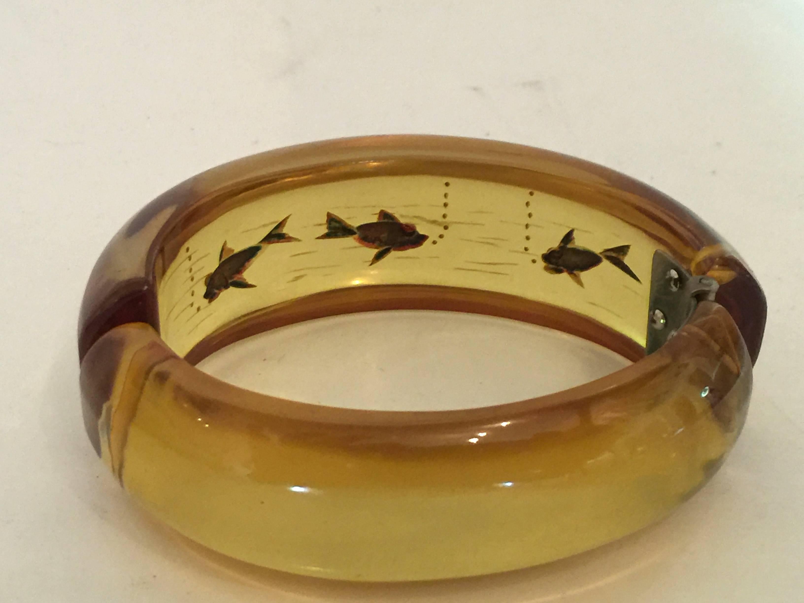 Most usually seen as bangle bracelets, rather than the more wearable hinged bracelet variety, all reverse carved fish hinged bracelets in bakelite are rare...but this one is super rare....Bubbles, waves, incredibly frozen in 'apple juice' fish are