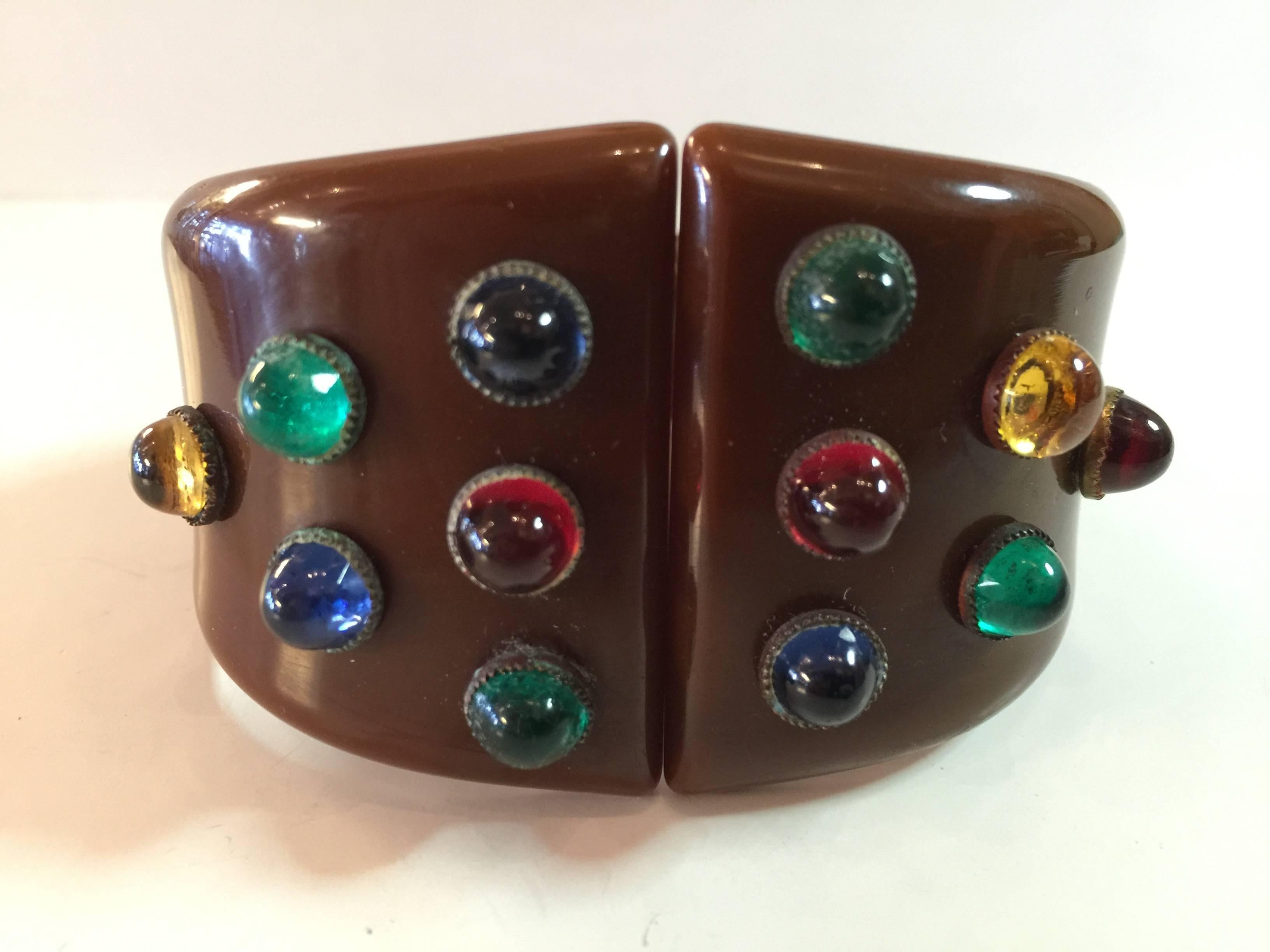 An unusual hybrid of bakelite and classic costume jewelry, this embellished rich brown bakelite hinged bracelet oozes sophistication and wearability. 12 Bezel set gemtone cabochons encrust the bracelet, a center open spring hinge mechanism variety