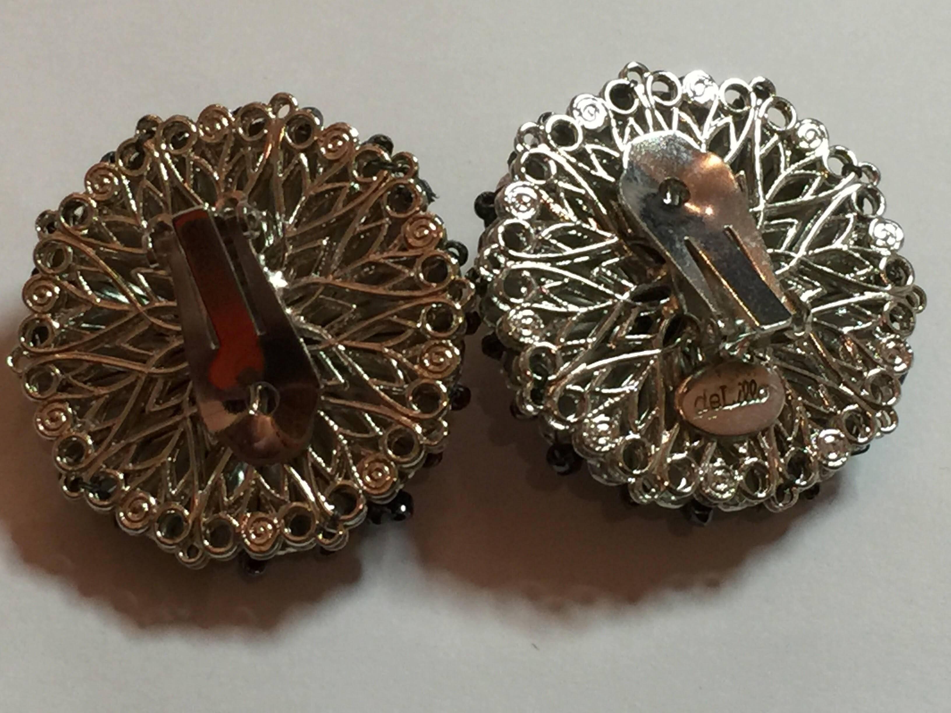 These William deLillo Seed bead Hematite and Silvertone Clip on Earrings date from the 1970s and reflect the Robert Clark for Miriam Haskell influence in much of a deLillo's intirciate seed bead design jewelry. Large domed discs over 1