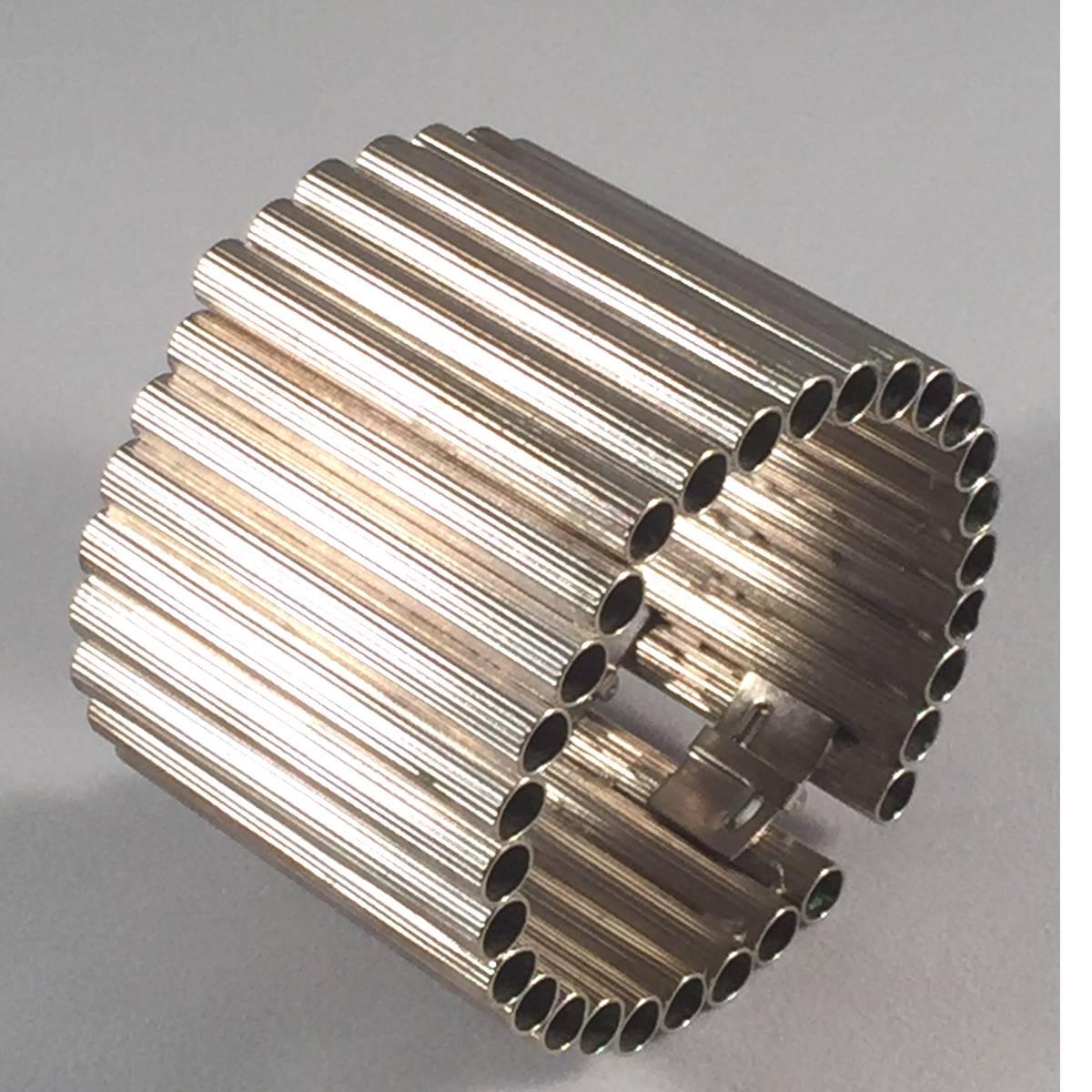 Modern and industrial is a tone not normally asssociated with master jewelry designer William deLillo, but this 1970s William deLillo Silvertone Tubular Modernist Hinged Bracelet is the exception to that rule. A master of many modes and mediums,