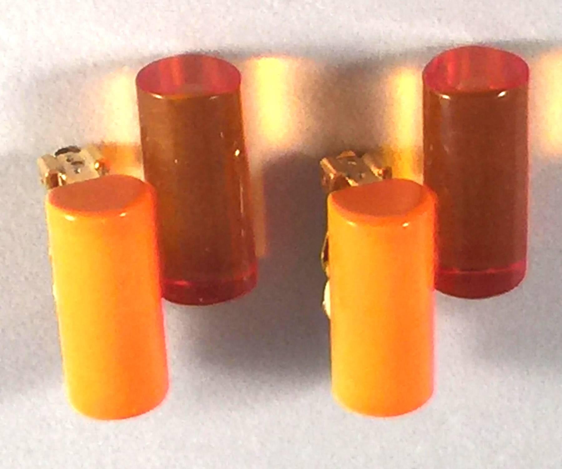 These 21st Century translucent and opaque orange and amber tubular acrylic earrings are assembled by the artist in the last five years using a combination of new old stock and newly acquired materials, The clip on mechanism is extant and functions