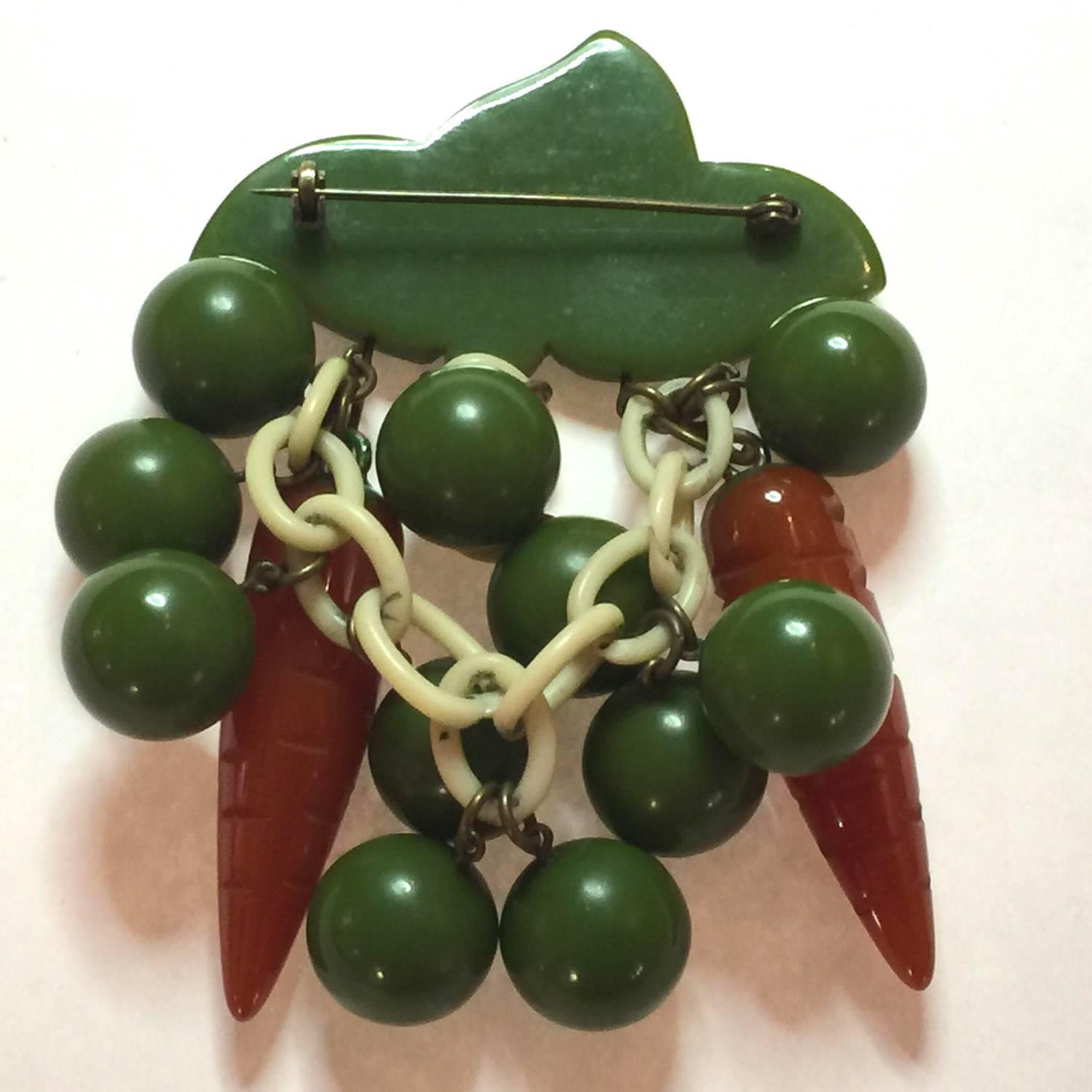 An amazingly humorous bit of bakelite magic, this 1930s Amusing Bakelite Peas and Carrots Figural Brooch/Pin sums up the essence of whimsy which so many admirers love about figural bakelite jewelry. A RARE vegetable pin, with this especially funny