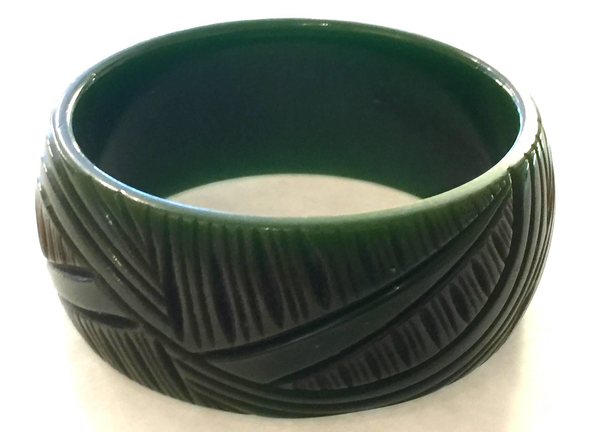 This classic green carved Bakelite bangle bracelet dates from the 1930;s and is a fine example of the carver's art utilized in making carved bakelite jewelry. This example has shallow carved stylized art deco foliate detail, and has a light, fresh