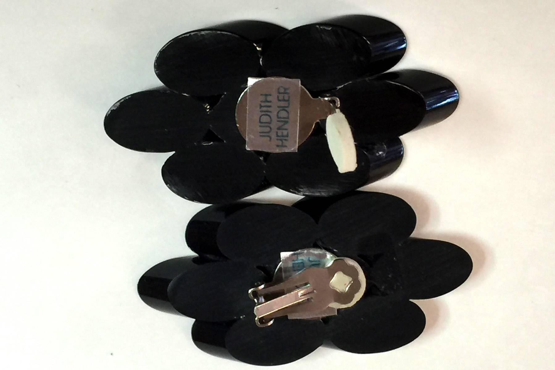 These ACRI-GEMS black opaque acrylic clip on earrings by Judith Hendler are of the late 1970's early 1980's era. Appearing a bit like flattened flower blossoms, they exude a quality which seems to bend space and time. Oblong and oval, these earrings