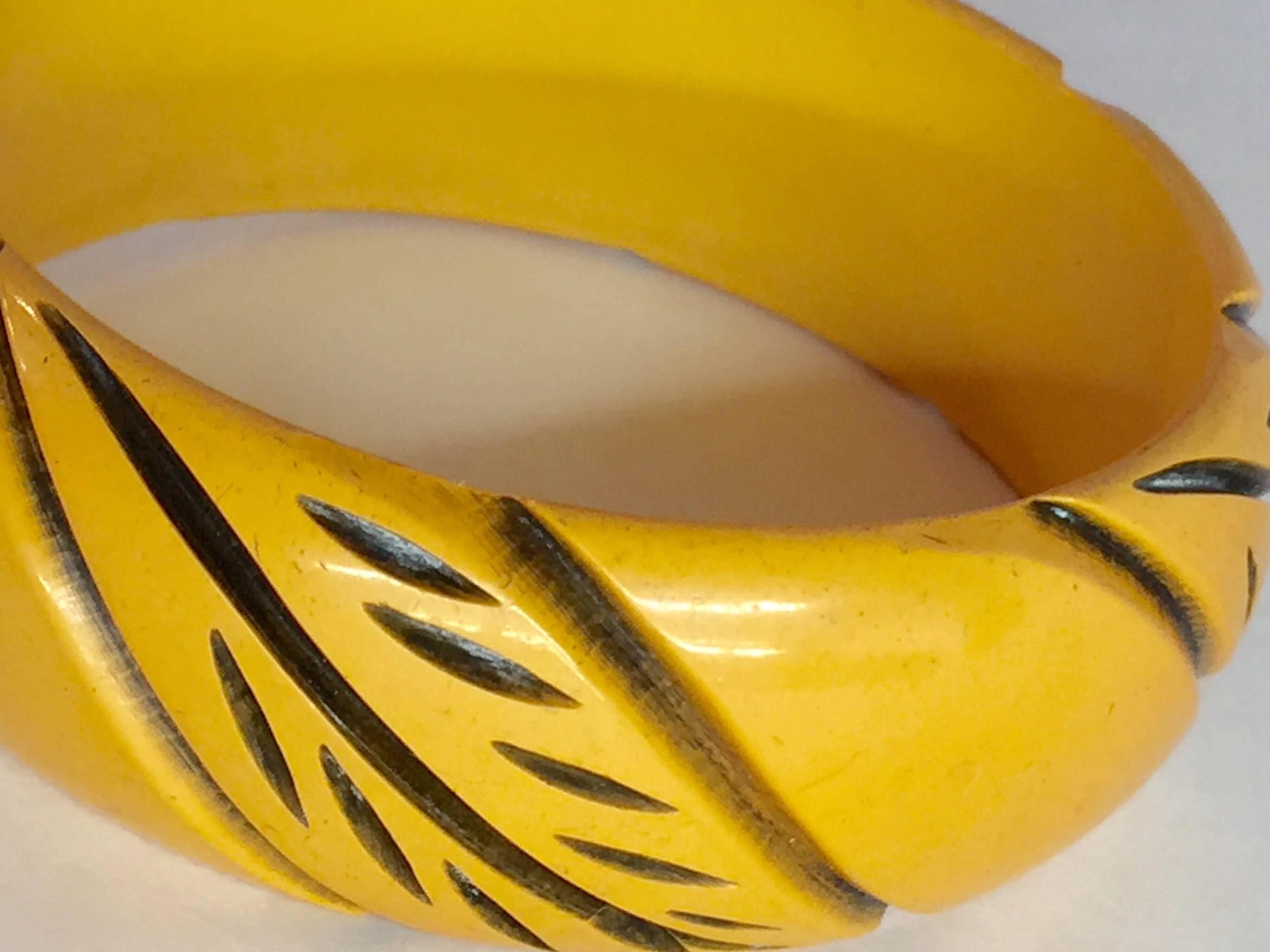 This unsual resin washed buttercream bakelite bangle dates from the 1930s and is a classic example of using resin washing to achieve a 2 color effect , amplifying the drama and detail of the hand carved leaf detail on this simple and lovely