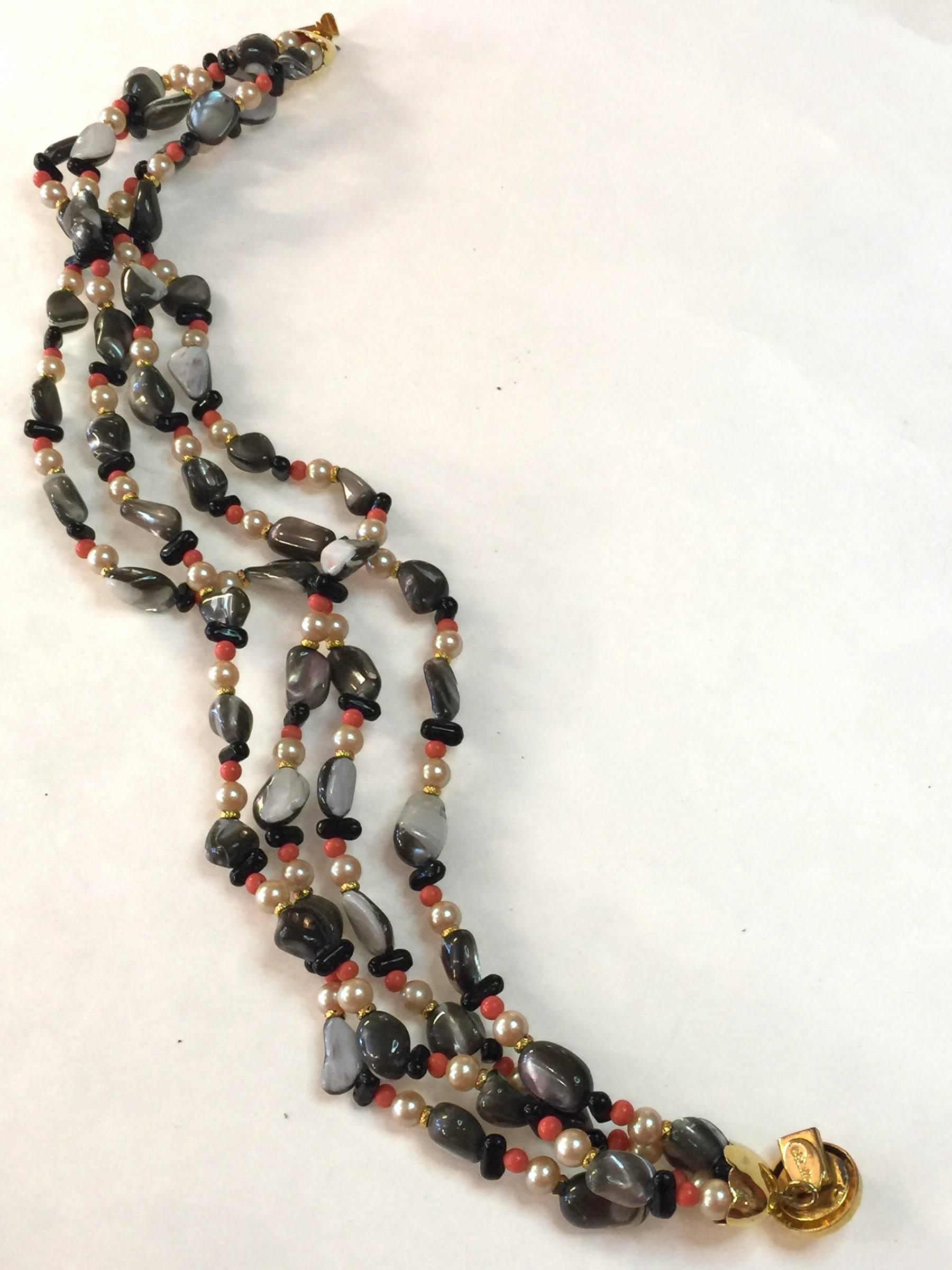 Simple and classic, yet exotic in tone, this multi strand necklace by storied designer William DeLillo is wonderful and wearable! Four strands of a cavalcade of undersea faux gems tumble and twist around the wearer's neck with style and elegance.
