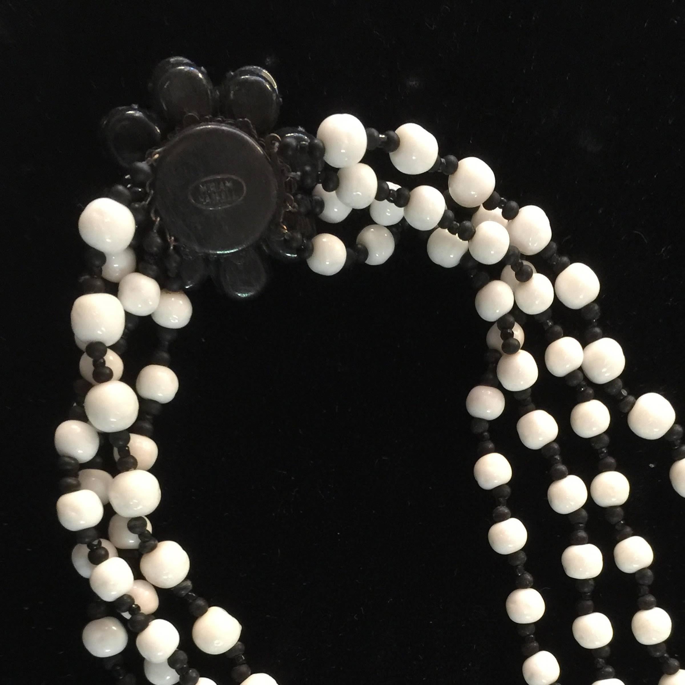 This wonderful 4 strand milk glass necklace by Miriam Haskell is chic and sophisiticated while also having the air of freshness and summer lightness Haskell florals are famous for, Black spacer beads add contrast in between the milk white glass