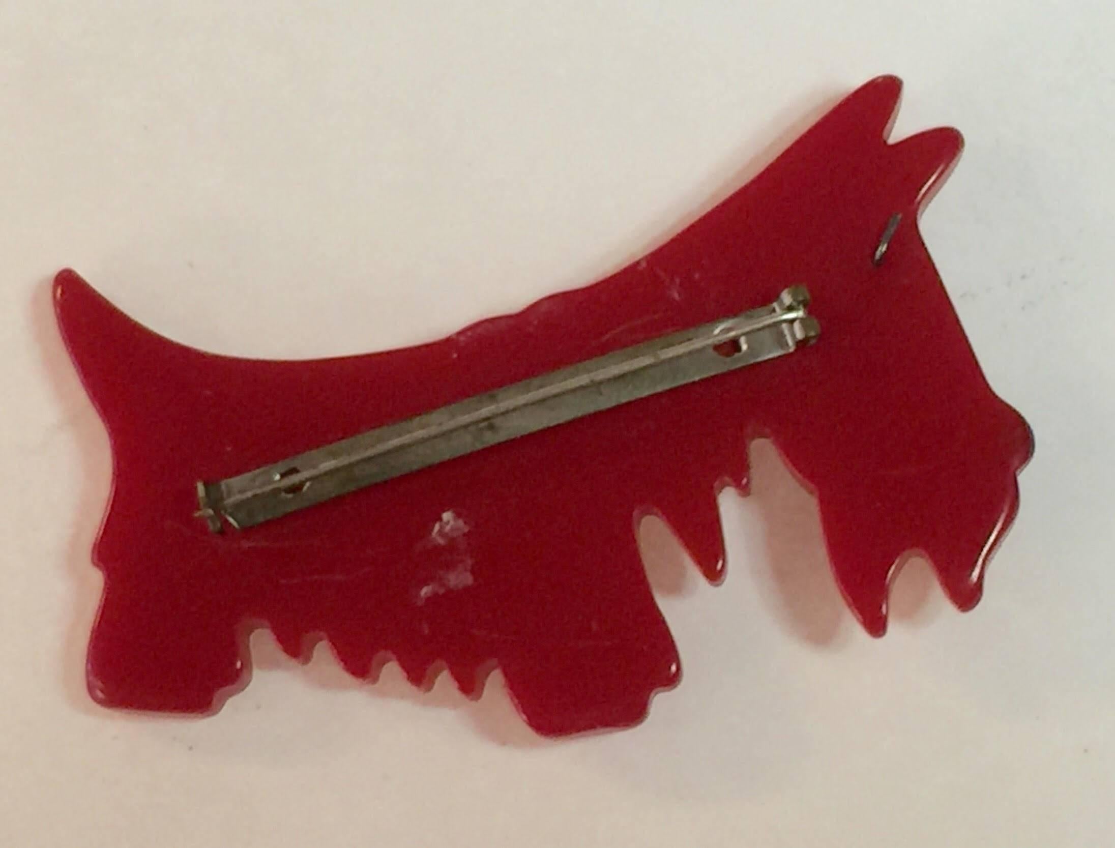 A classic of both bakelite and art deco 1930s culture, this red BAKELITE scotty pin is iconic. Lightly carved with detail which is both whimsical and elegant, this adorable pooch will make any outfit more upbeat and fun! 3