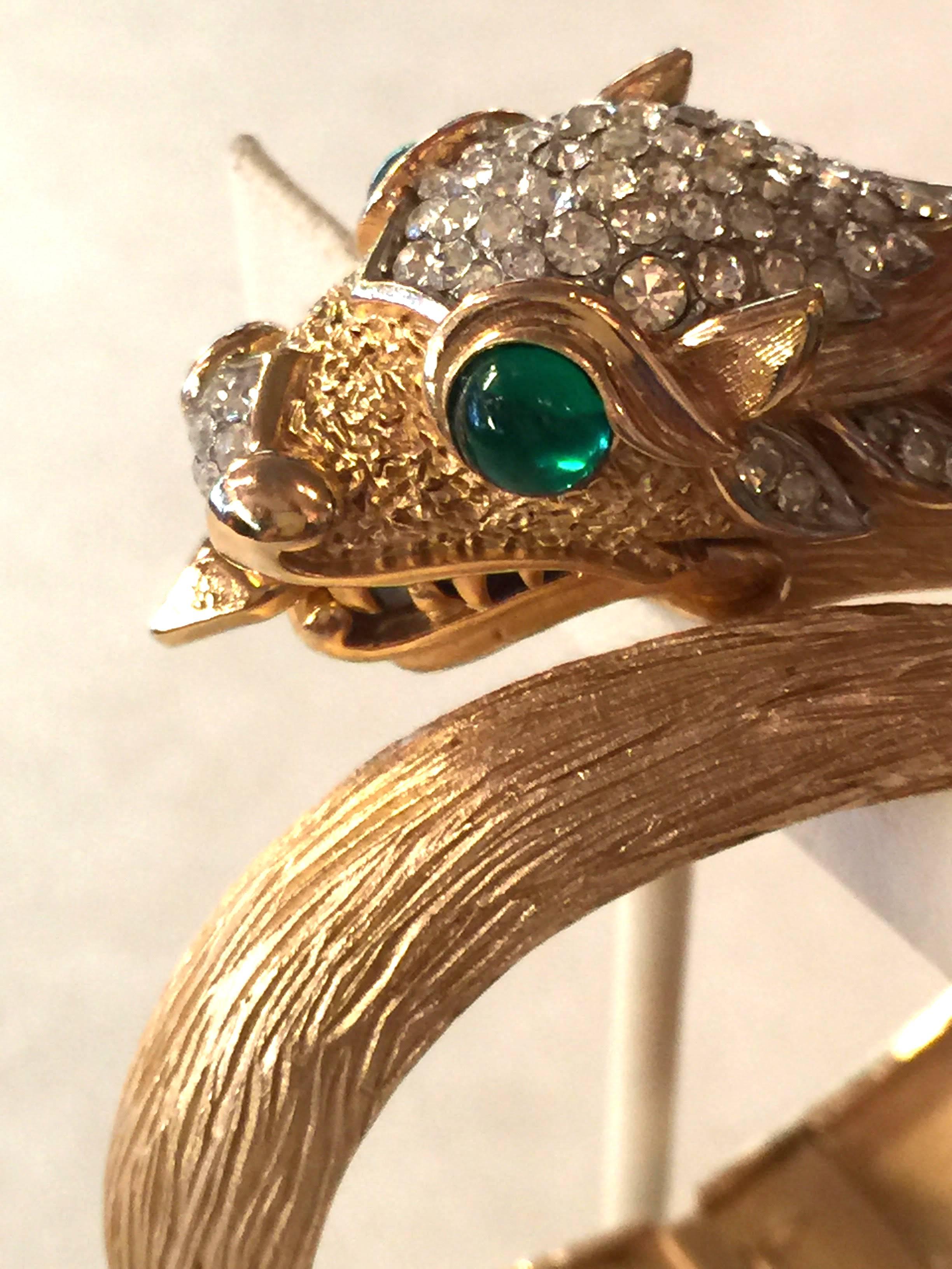 Classically elegant and iconically stylish, this Trifari Matte Brushed Goldtone Diamante Green Cabochon Dragon Hinged Bracelet dates from the 1960s and is representative of a style of fine jewelry popularized by BULGARI and executed in non precious