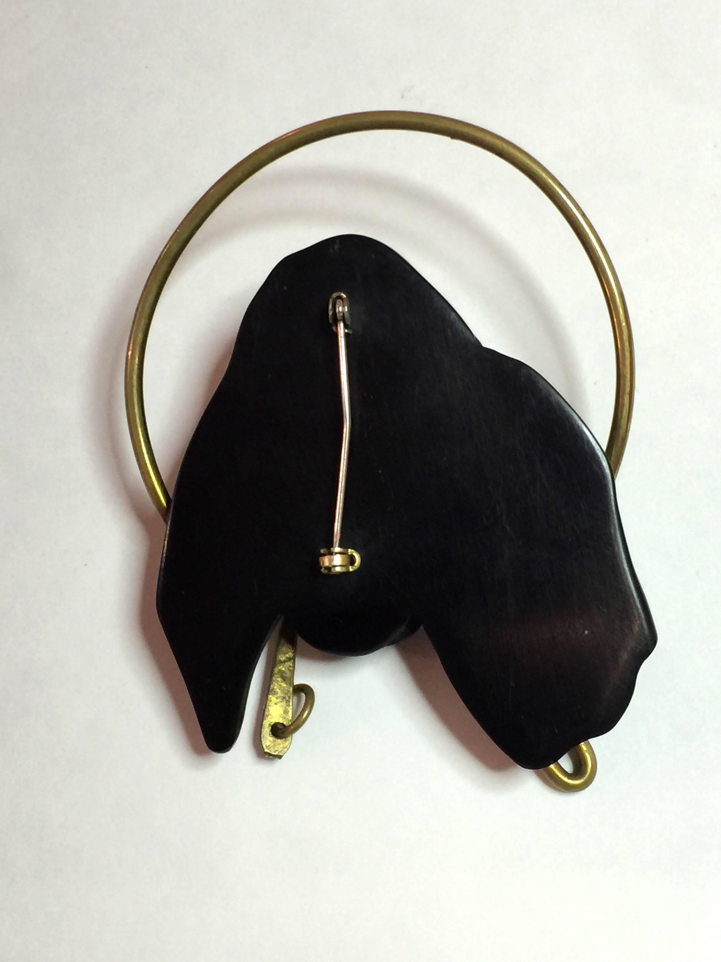 A rarity indeed, this 1930s  Black Bakelite DOG with Brass Leash in Mouth Brooch Pin, is part of a series of pins utilizing heavy gage brass wire for decorative effect and accent in unusual bakelite brooches. A wonderful hound with floppy ears and