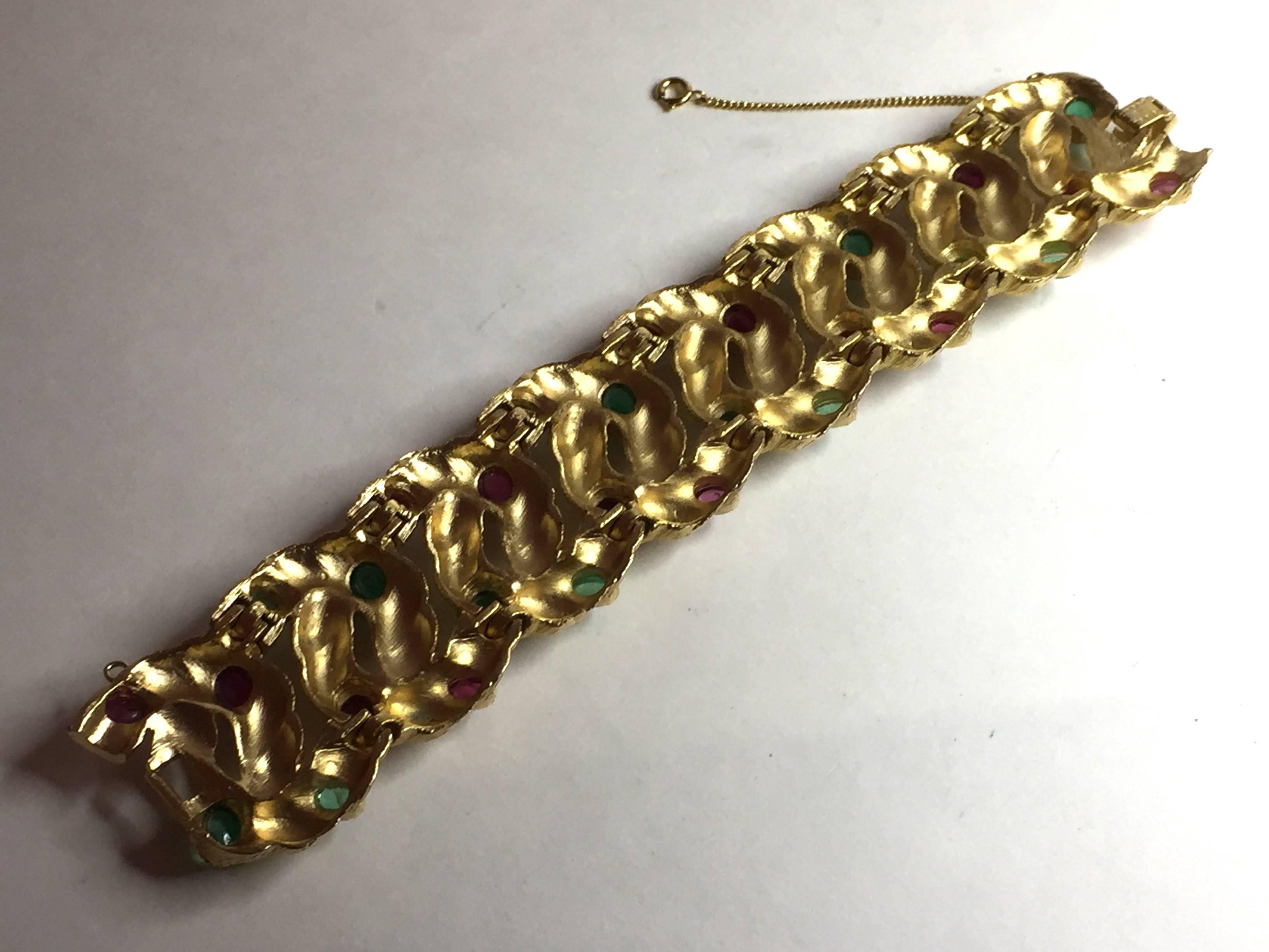 This listing is ONLY for the 1960s TRIFARI Brushed goldtone bracelet embellished with scored detail and gem tone faux ruby and emerald cabochon stonework.The bracelet is 7
