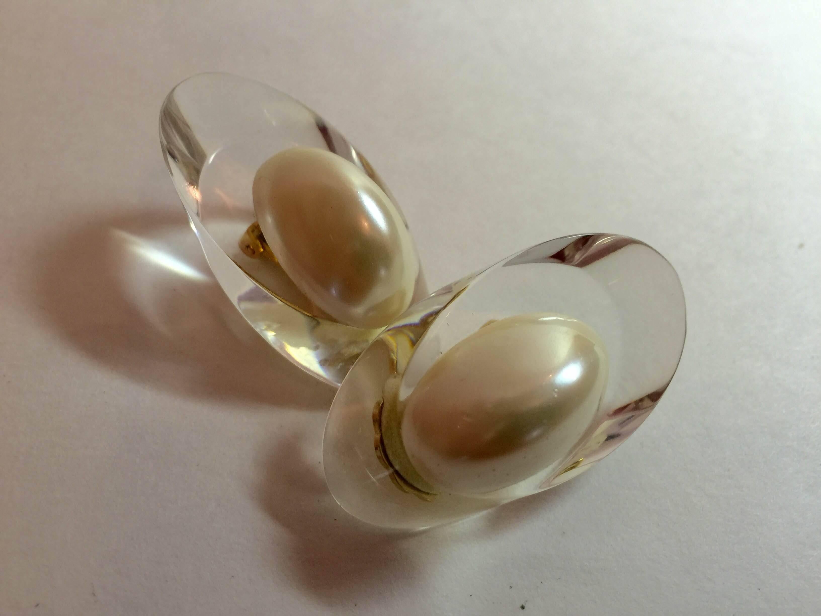 These ACRI-GEMS water clear acrylic and pearl clip on earrings by Judith Hendler are of the late 1970's early 1980's era. This shape is referred to as 'fingernail' flattened long clear acrylic ovals, and have a long flat backed oval pearl as