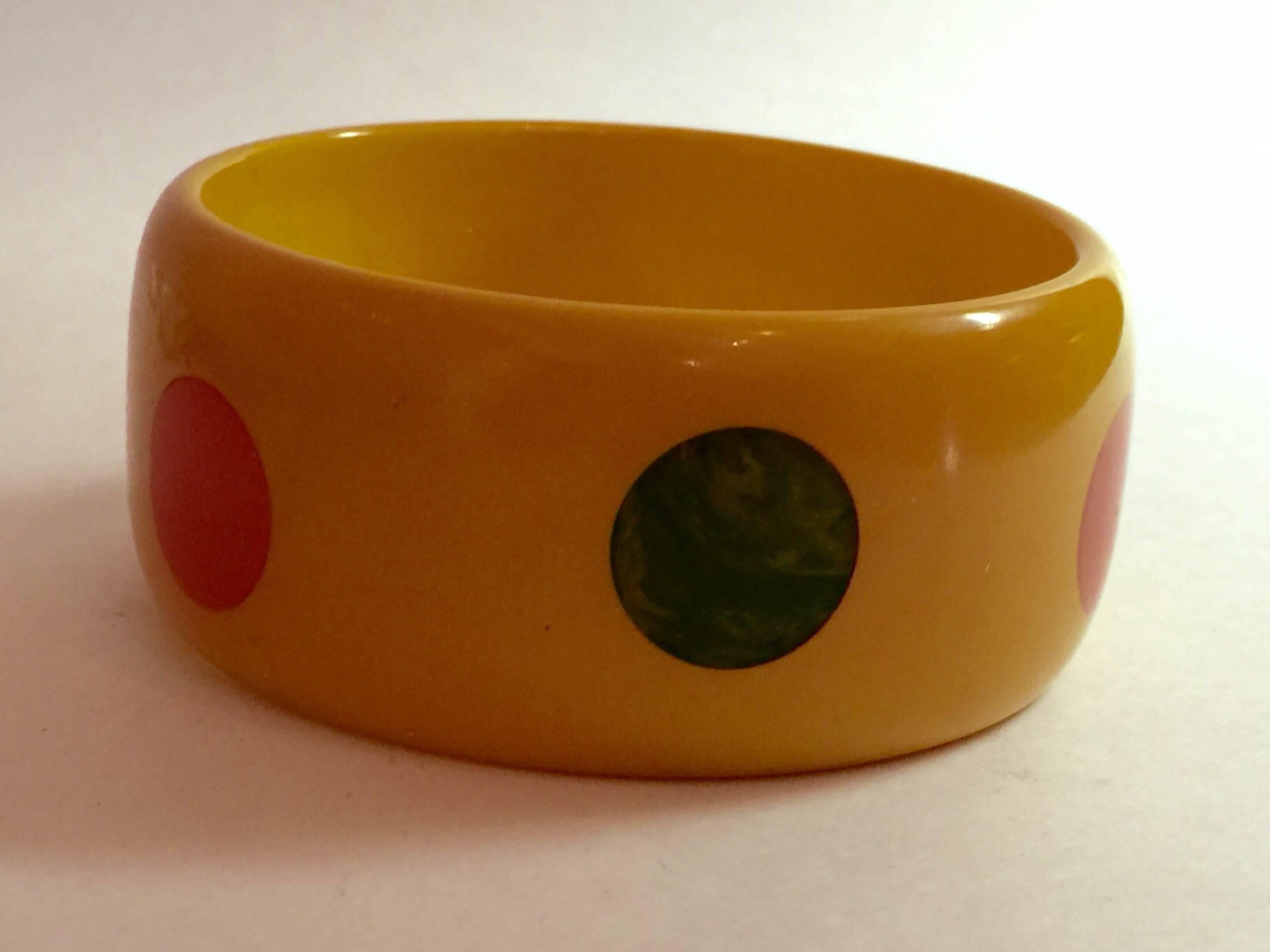 This 1930s Bakelite MultiColor Polka Dot bangle Bracelet is Flat Walled, in cream bakelite with alternating placement polka dots laminated in ornage and green. This is not a thick walled chunky bangle, so it fits small,  medium and even some larger
