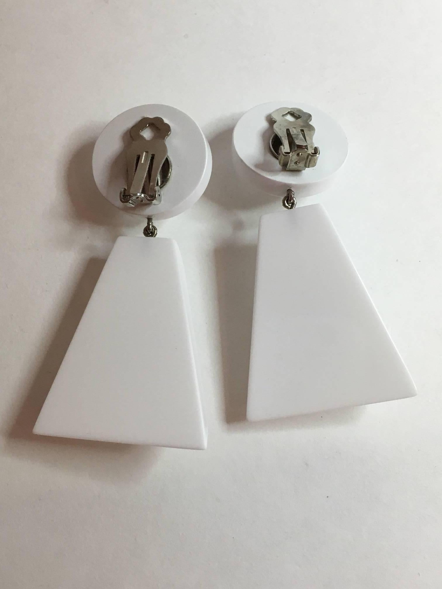 These lovelywhite acrylic earrings with white disc tops with circular rhinestone detail suspend trapezoidal white acrylic drops. The discs are under 1
