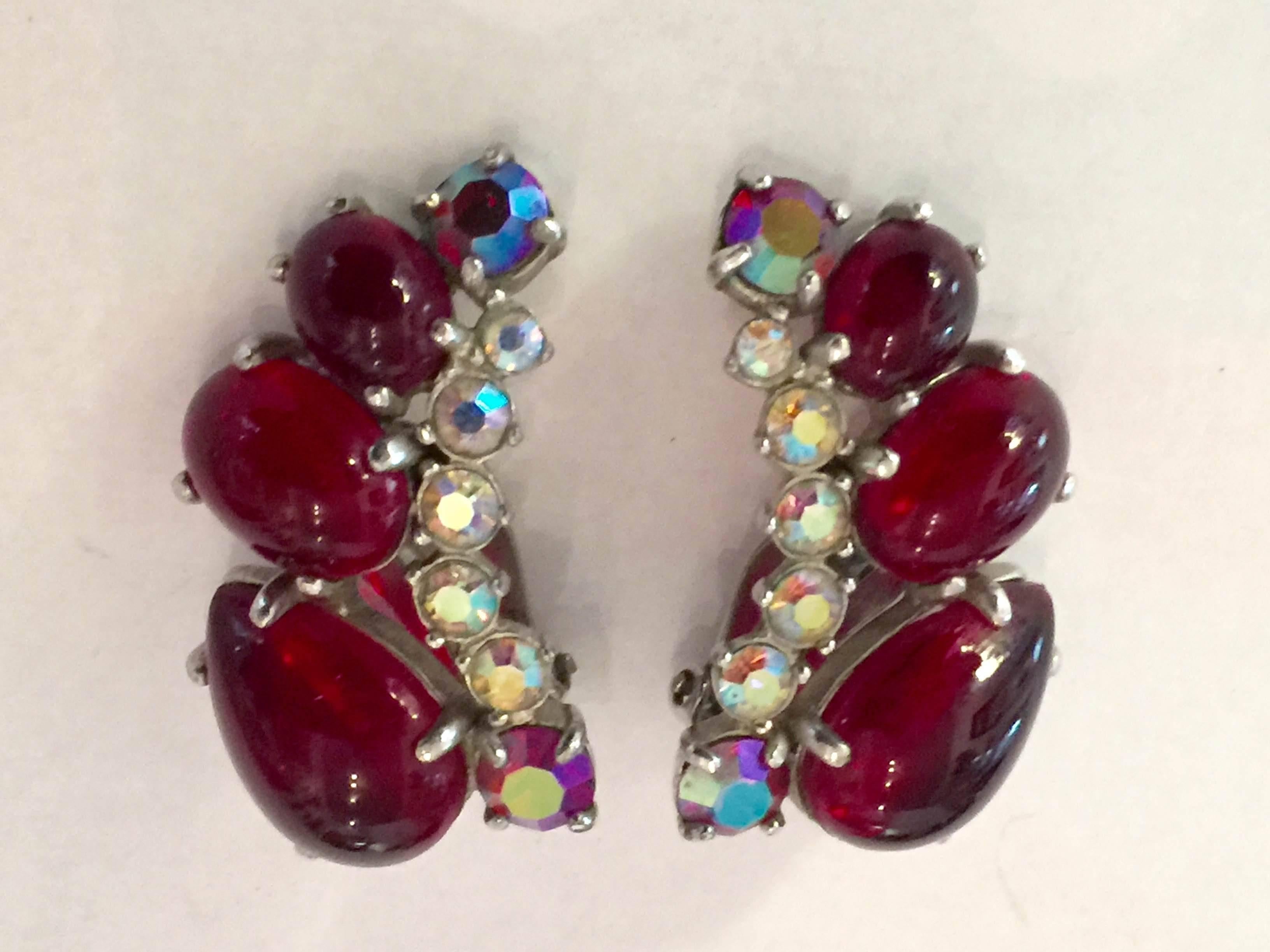 An opulent pair of earrings by Schiaparelli, exhibit the classic 50's crescent shape, so popular in the period. Graduated size brilliant red cabochons trace the line of the ear, and are edged with luscious aurora borealis stonework. Original clip on
