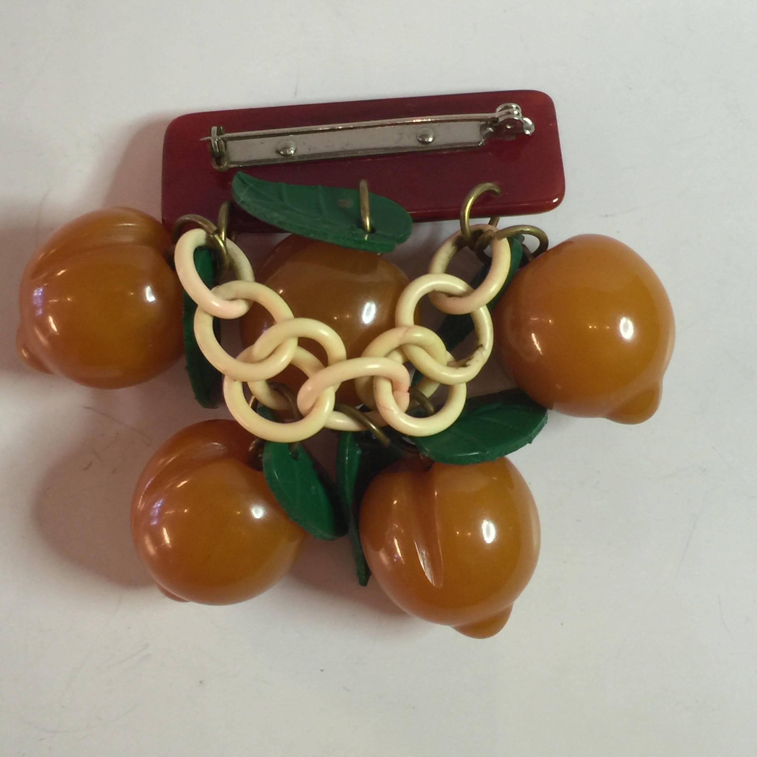 This classic art deco 1930s bakelite fruit pin is a rarity. Cherries are the most common....with most other fruits being much rarer. Apricots, particularly rare. A resin washed rectangular barpin  is carved and colored to ressemble tree bark, and 5