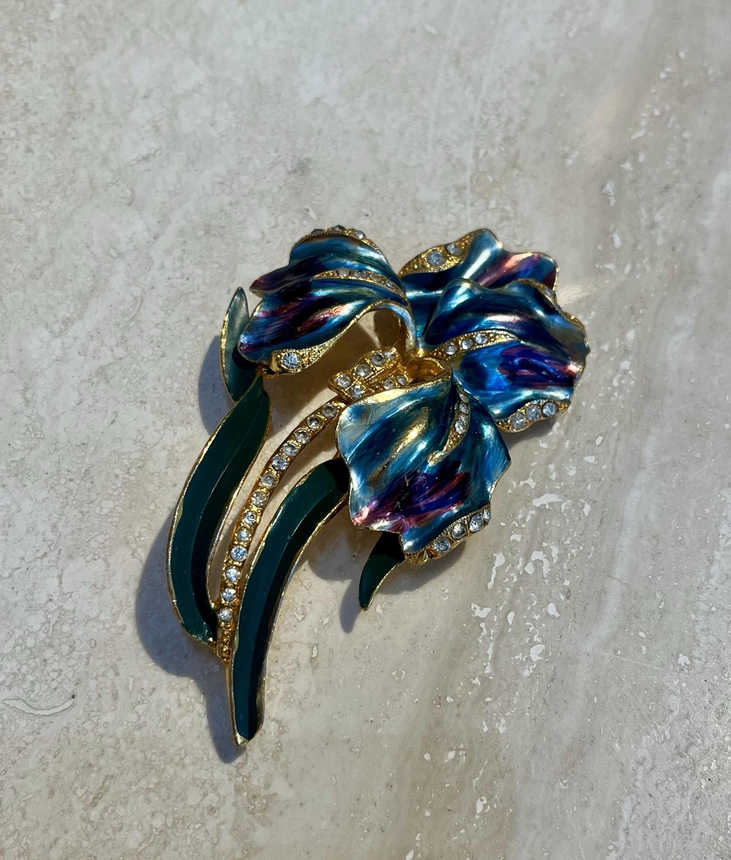 This Vintage Coro Enamel Iris Brooch is a beautifully crafted piece of jewelry that highlights the artistry and elegance of the Coro brand, renowned for its fine costume jewelry in the mid-20th century. 

This brooch features an iris flower motif,