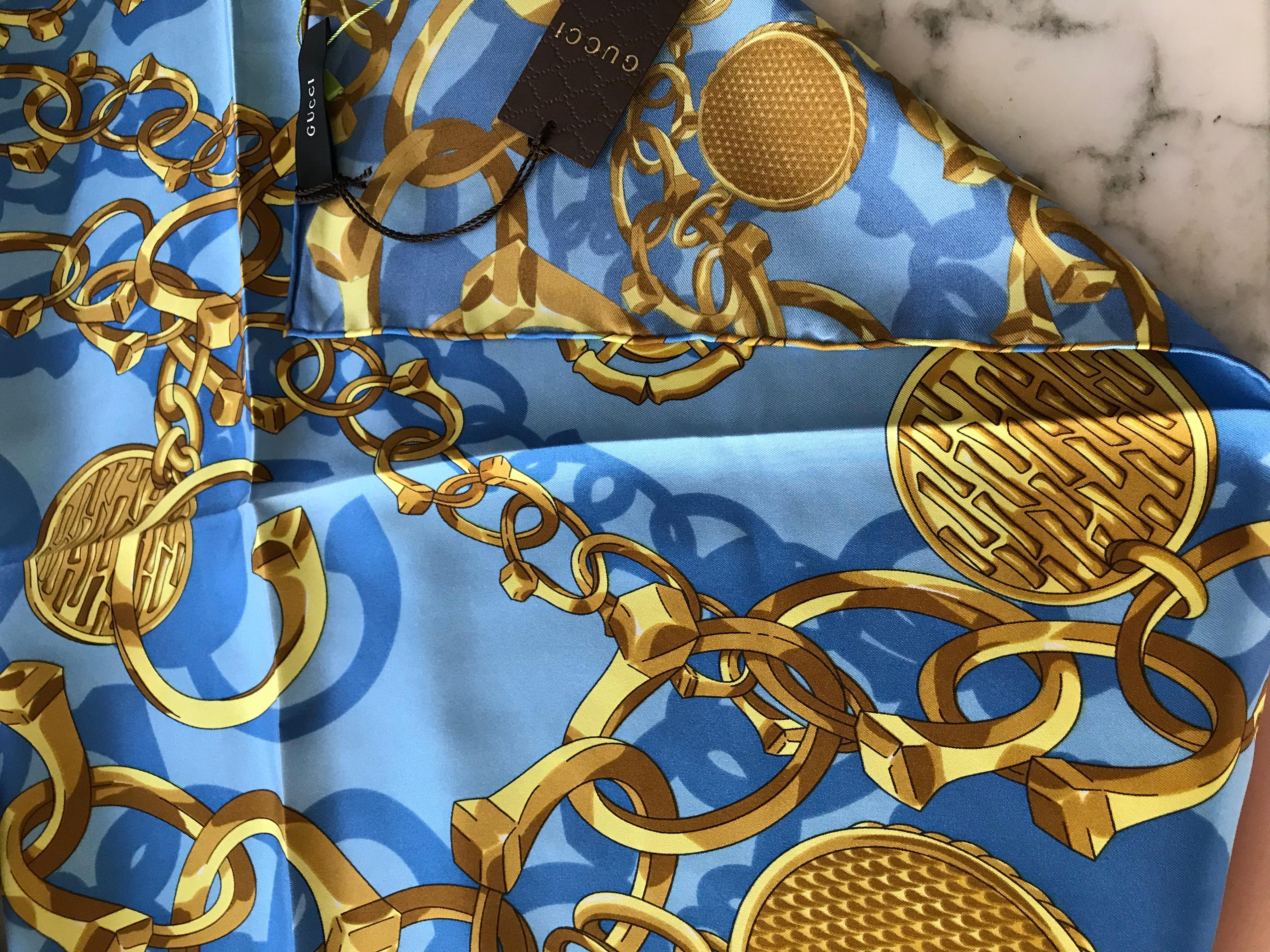 Dead stock Gucci ( 10 yrs old) Blue and gold chainlink print silk scarf with hand stitch hem.
Scarf is in excellent condition.  
24” X 24” 