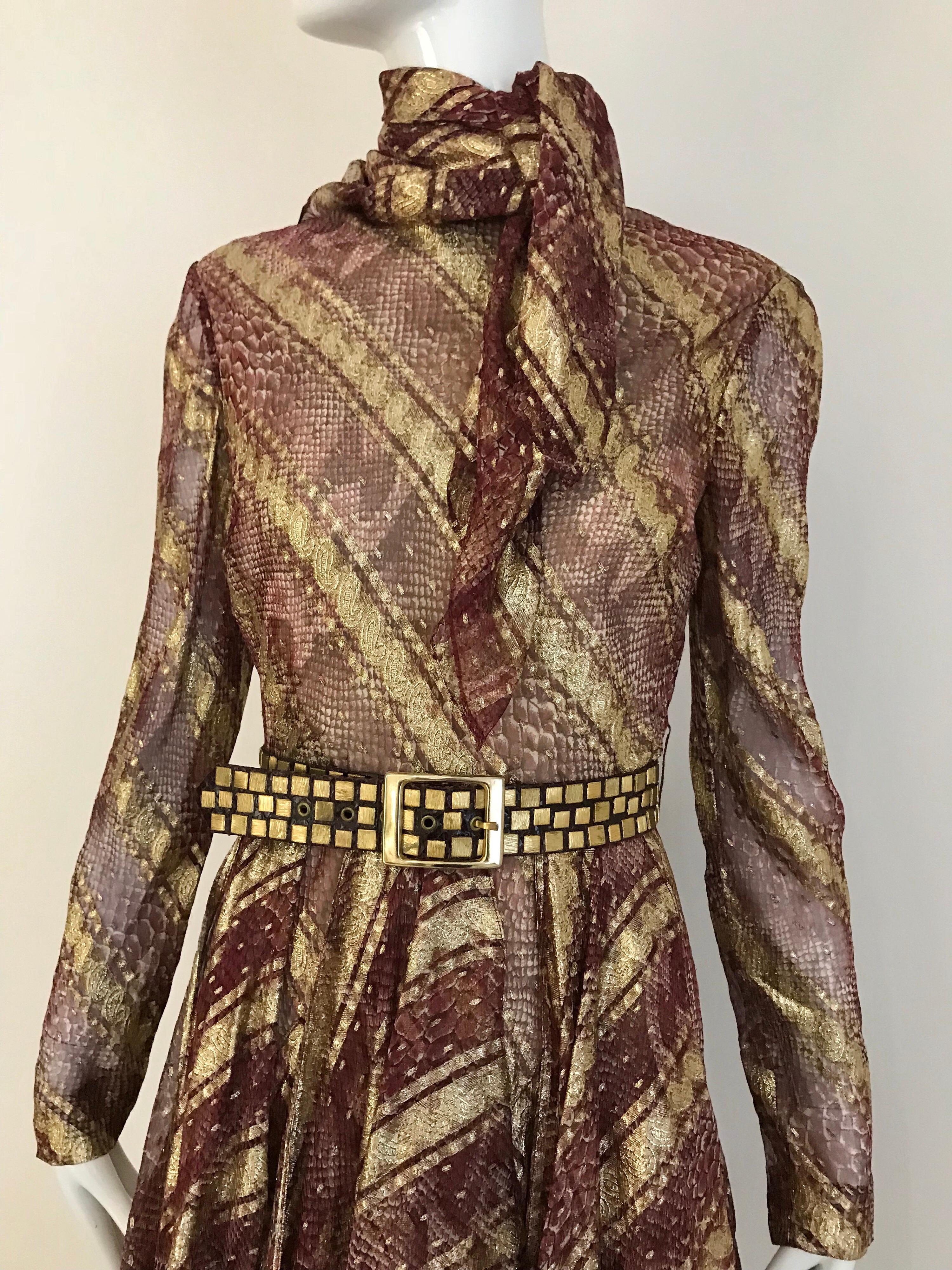 1970s Bill Blass snake skin like print dress in metallic plum and gold with handkerchief hem. Wine colored, printed python chiffon is enhanced with stripes of gold paisely trim.
Dress comes with belt and detachable silk scarf. Perfect cocktail
