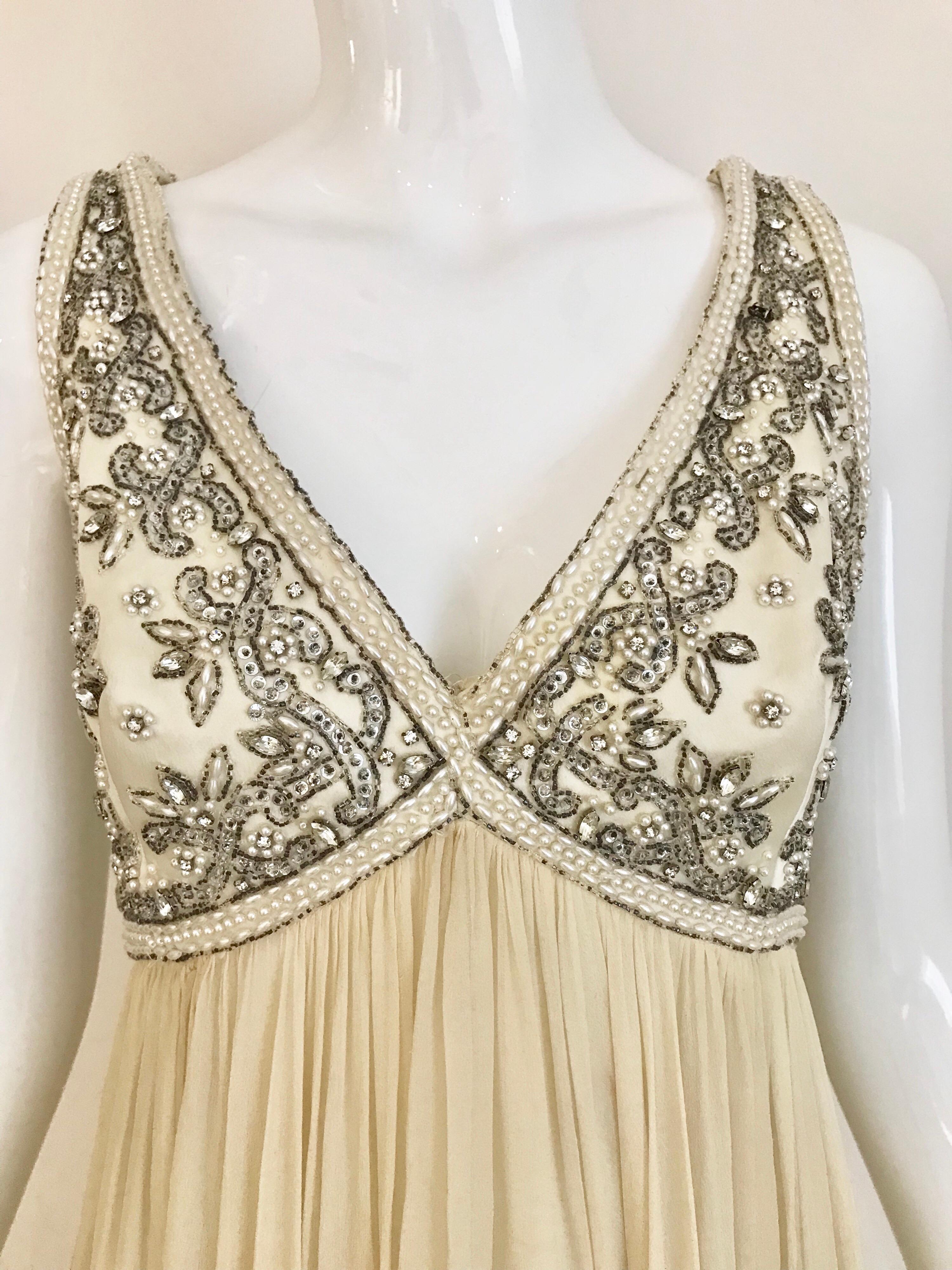 This elegant 1960’s Elizabeth Arden sleeveless is a dramatic creation. The bodice is encrusted with pearl-like beading and sequins. There is a nice blend of the off white silk on the bodice and the cream colored silk chiffon bottom, which gives the