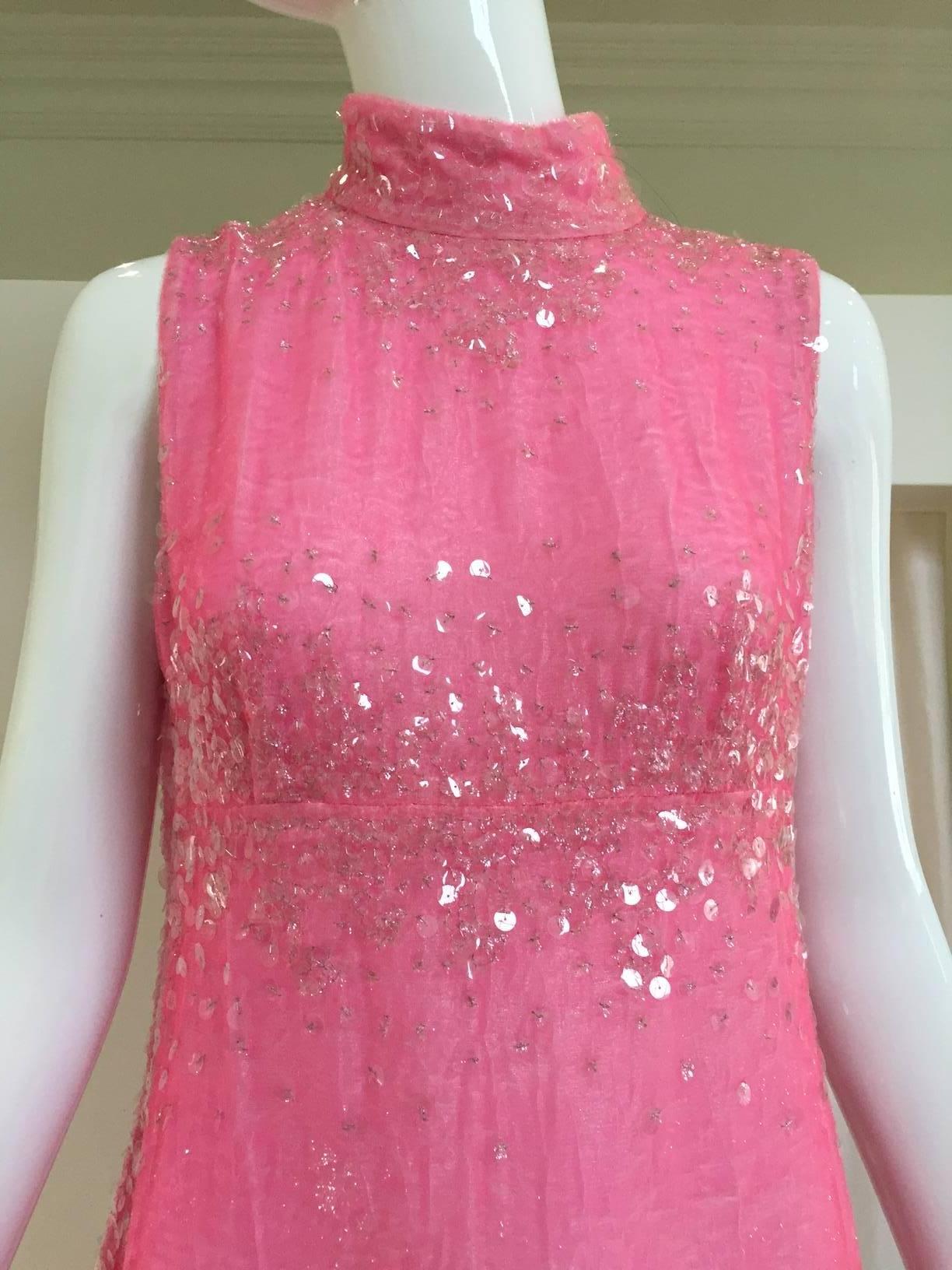 This stunning Chanel gown has a mock collar that is secured by 3 clear Lucite signature “CC” buttons on the nape of the neck.  The collar, shoulders, bust and hemline are all highlighted with shimmering sequins that also flow down the edges of the
