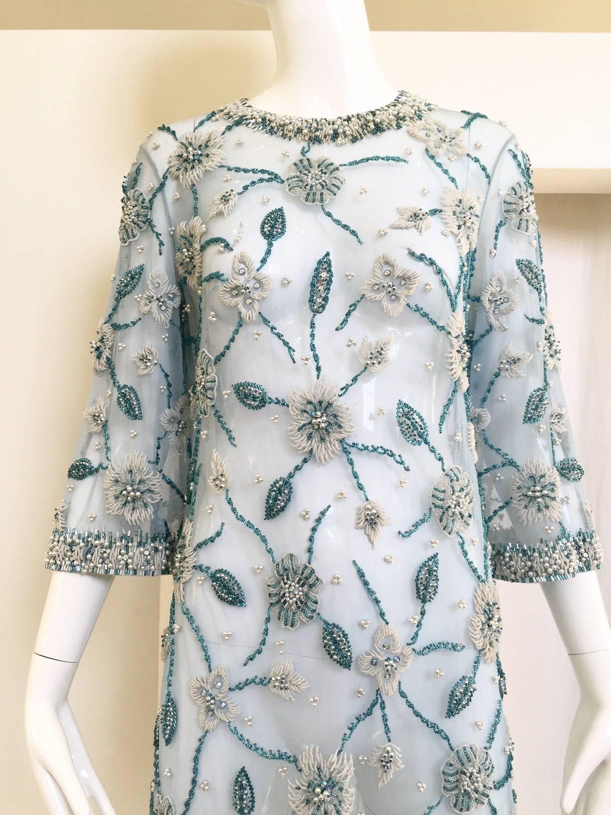 Incredible 1960s Sheer blue mesh tunic has floral designs created with blue and white beading, which are highlighted with rhinestones.  The collars and cuffs are emphasized with heavy beading.  The side slits are 30.5” long.  
Size: 4/6  SMALL -