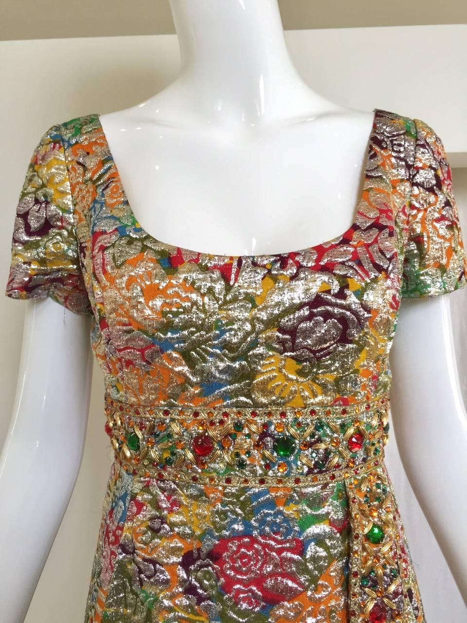 This vintage 1960s multi color metallic silk brocade is in rich jeweled tone adorned with red, gold, yellow large sequins embellishment on the waist. Dress has empire style waist with belt that attached and hang with beads. scoop neckline. Jackie O