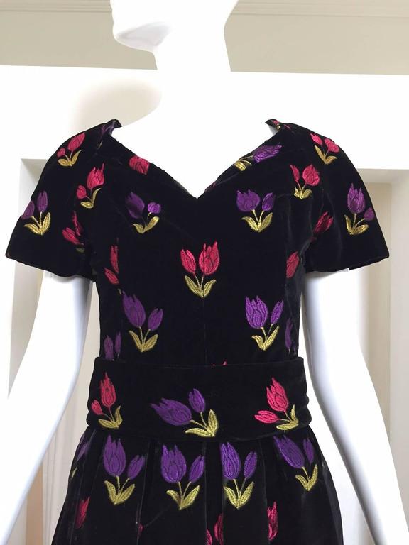 Beautiful 1950s Black velvet cocktail dress embroidered in purple, Pink  and green tulip. 
sweet heart neckline and the waist has a cummerbund type waist . Size: Small (2-4)
Bust : 36