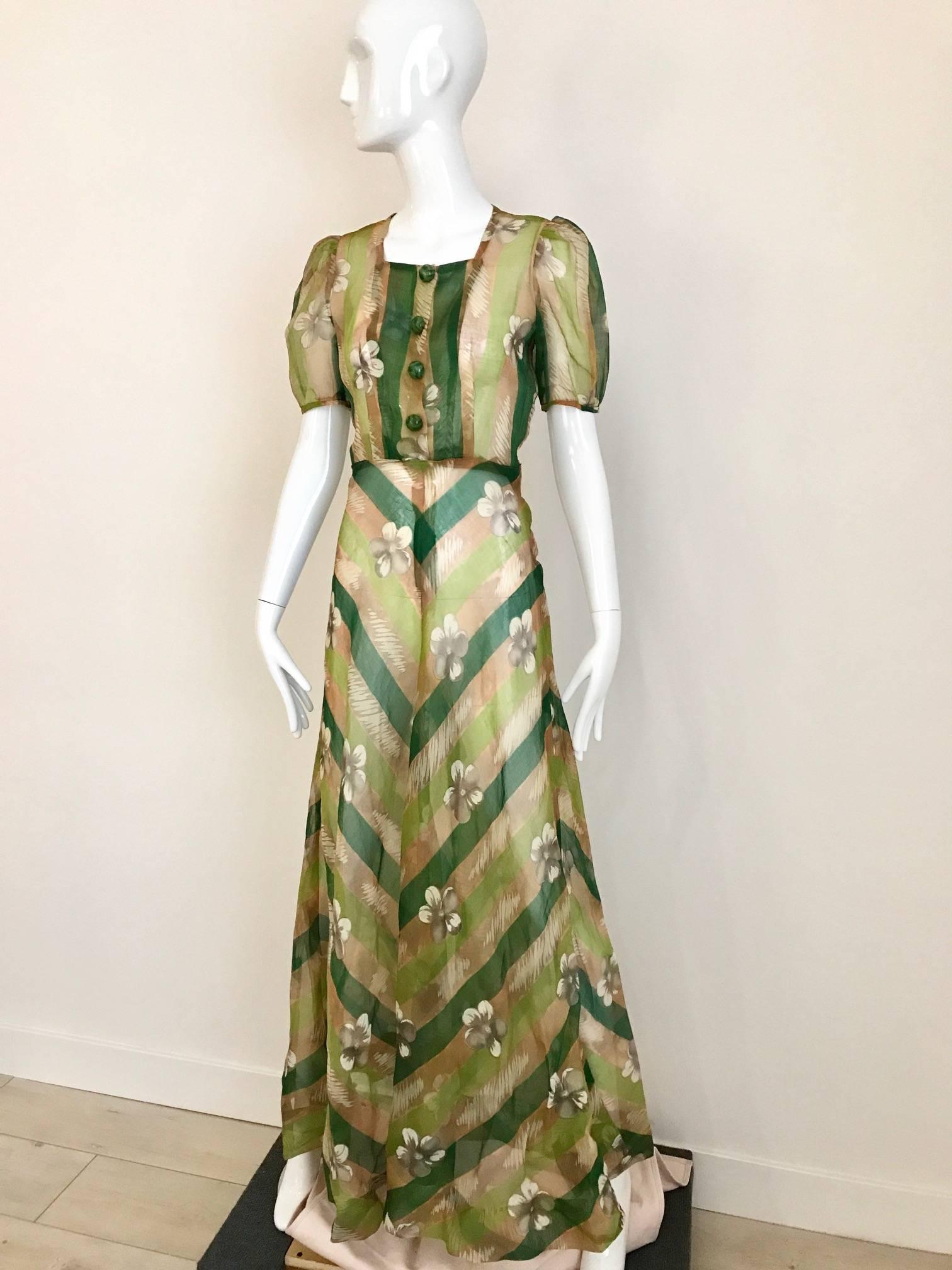 1930s Art deco print silk organza dress in green, tan, white and grey floral and chevron print. 4 lucite snap on front button  and zip on the side. 
Size: 4/6 small