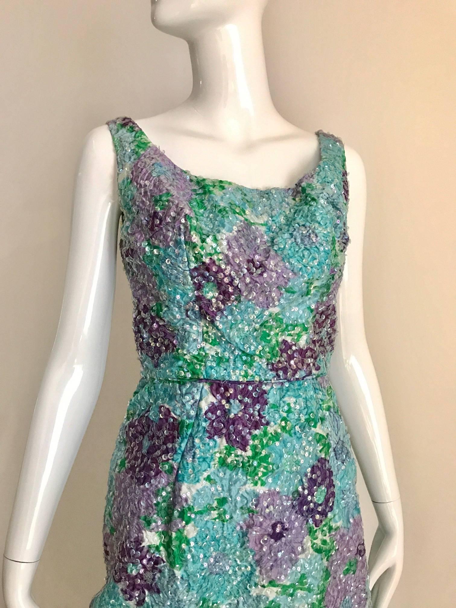 Late 1950s and early 1960s vintage cotton watercolor  floral print sheath dress. Iridescent clear sequins sewn all over the flower prints. Sleeveless Sheath wiggle style. The skirt has a back walking slit. Nylon zipper up the back. Bodice lined in