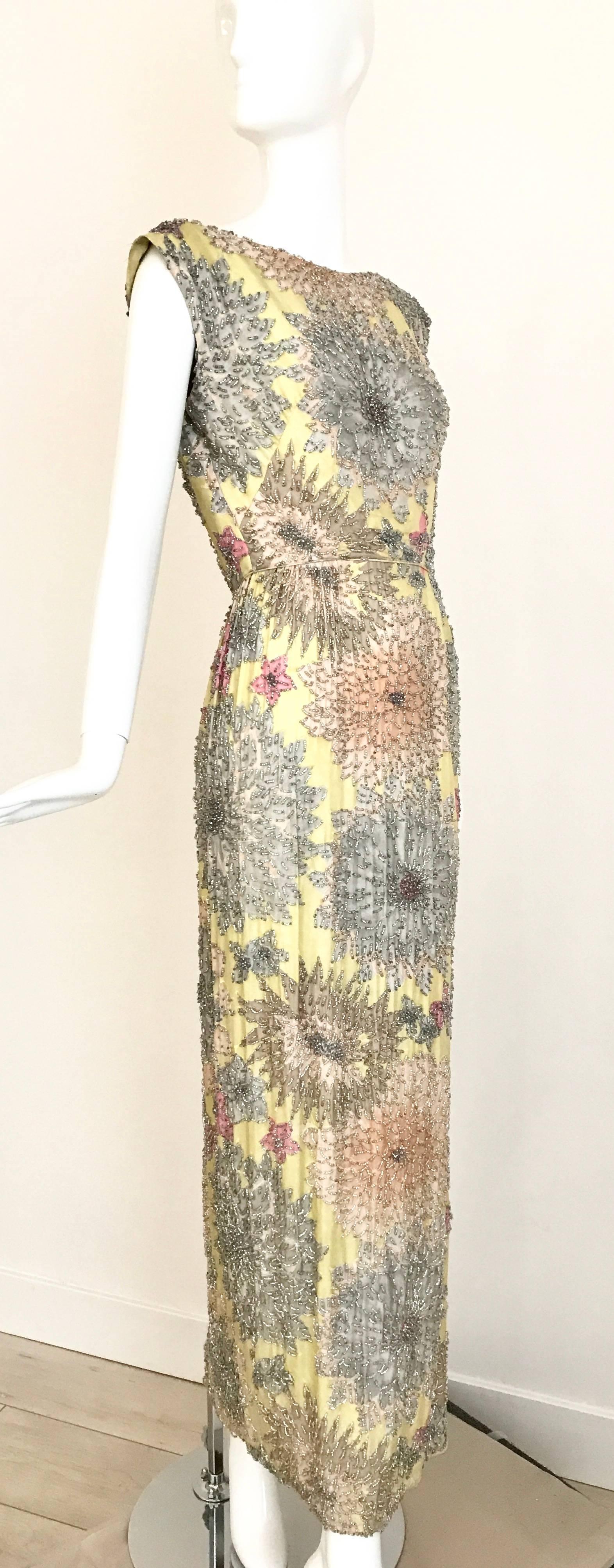 Beautiful Heavy beaded 1960s Malcolm Starr sleeveless cocktail dress.
Light yellow silk twill covered in dense clear beads over floral pattern in soft grey, yellow, peach and light pink. Sexy and elegant at the same time. Simple sheath dress with