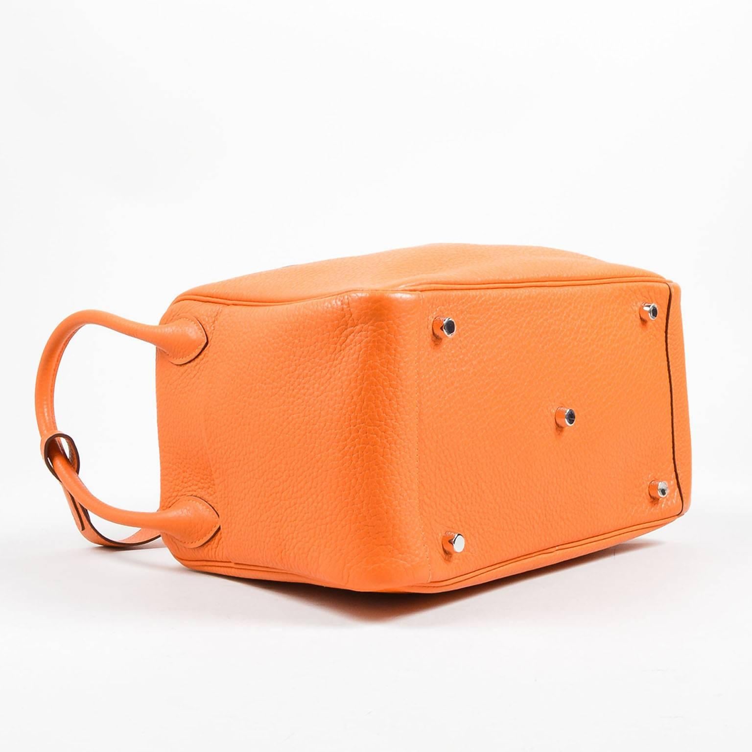 From 2010, the "Lindy" satchel by Hermes is constructed of supple and slouchy "Clemence" leather in a bright orange tone. Silver-tone hardware. Dual zipper closure at top. Twist-lock fastening. Rolled handles at sides; shoulder