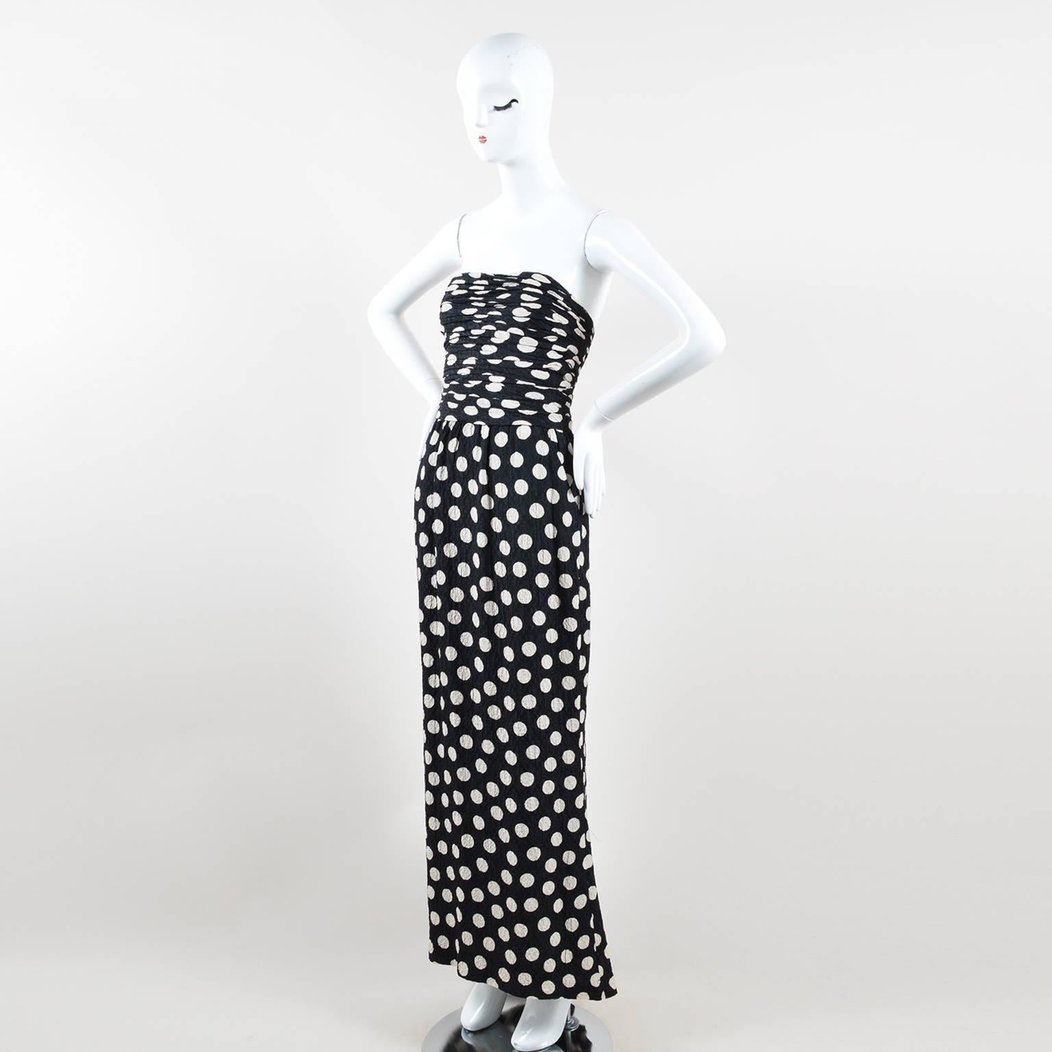 Lightweight hammered silk strapless evening gown. Black base with cream polka dots throughout. Ruched pleating throughout bodice. Light boning throughout bodice for shape and support. Column-silhouette skirt. Slant hip pockets. Back hem is slightly