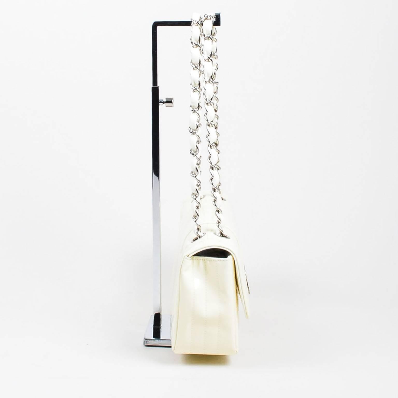 Mix up your handbag collection with this ultra chic, modern shoulder bag. A unique collector's item, this piece adds instant style cred to any ensemble. Cream quilted patent leather with silver tone hardware. Signature chain shoulder straps. Front