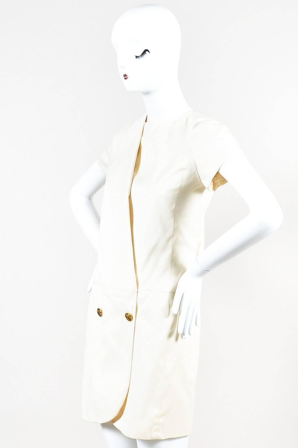Vintage Chanel dress from the "CR 90" Collection features a cream cotton with short sleeves and a rounded neckline. Mid-thigh length, rounded hemline. Drop waist. Wrap front with gold tone clover button closures. Slanted folded panel at