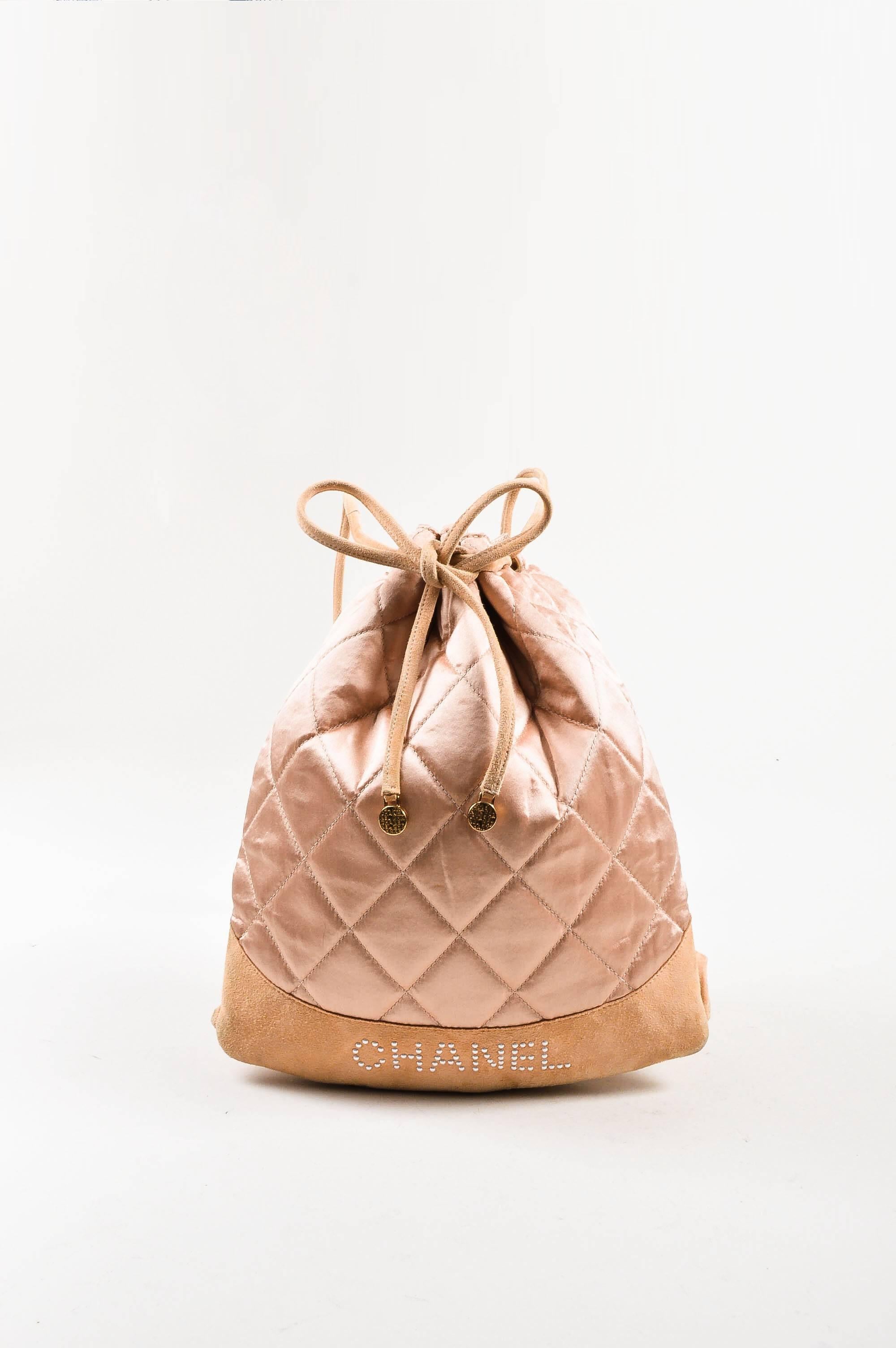 Whimsical and fun drawstring backpack by Chanel. This blush pink piece features quilted satin and suede with a lightweight design. Faux pearl 